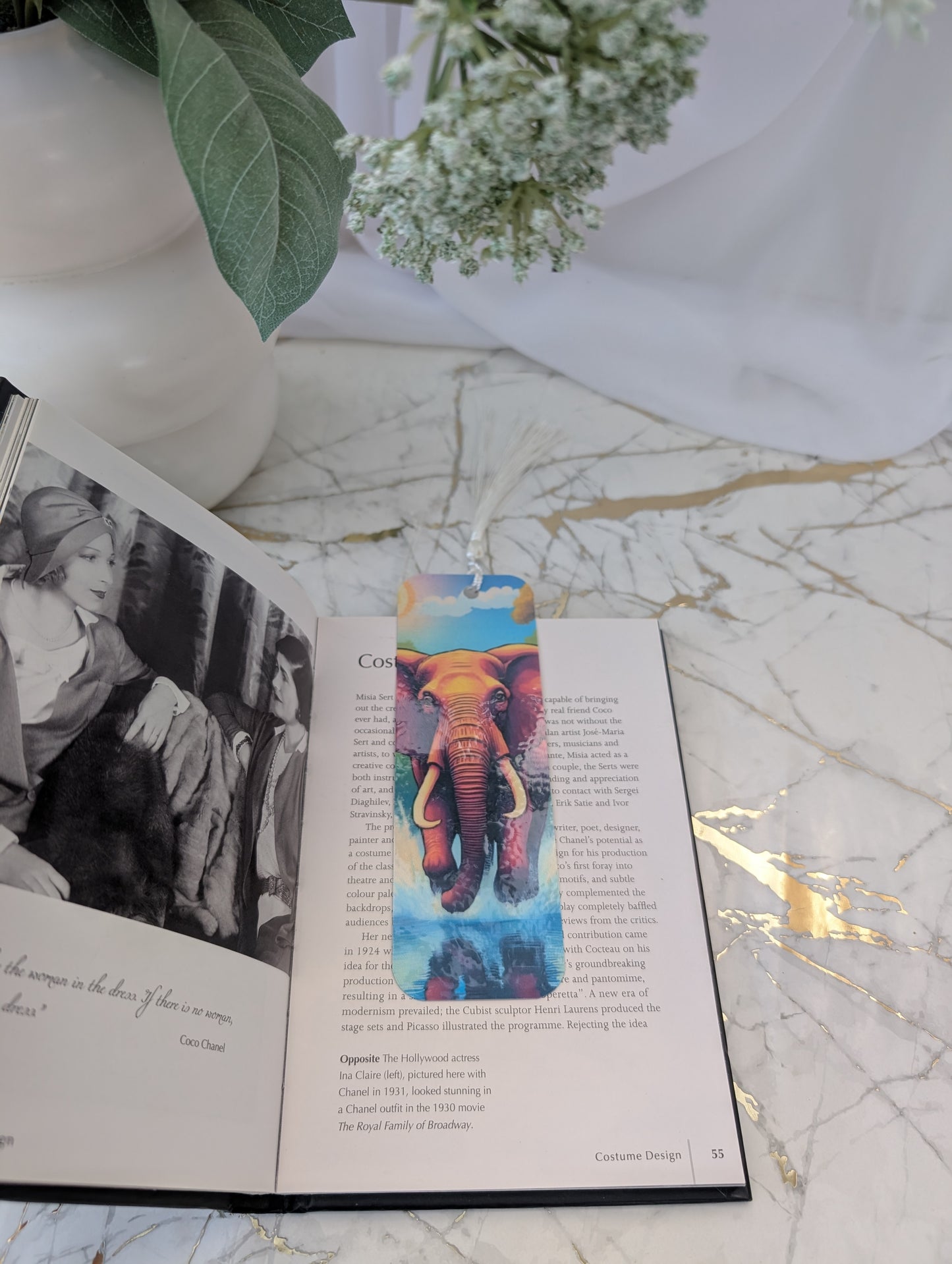 Colorful elephant bookmark on an open book with a vase and flowers in the background