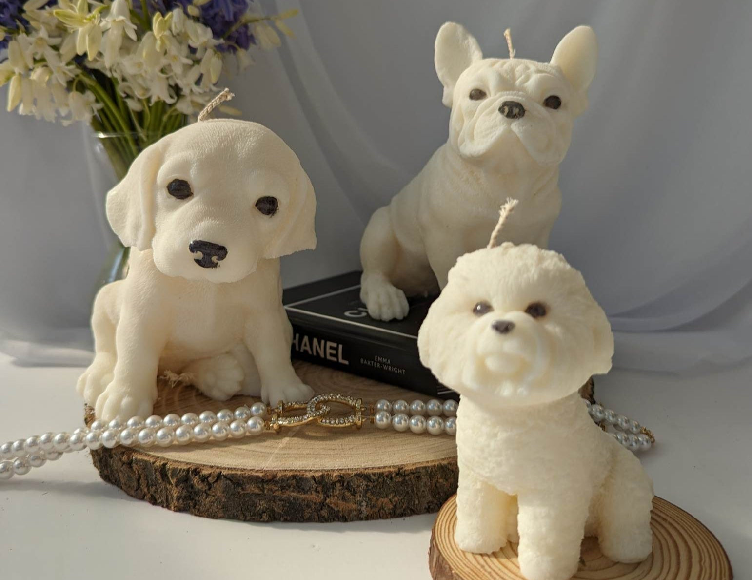 Three white dog figurines on wooden bases with a blurred background