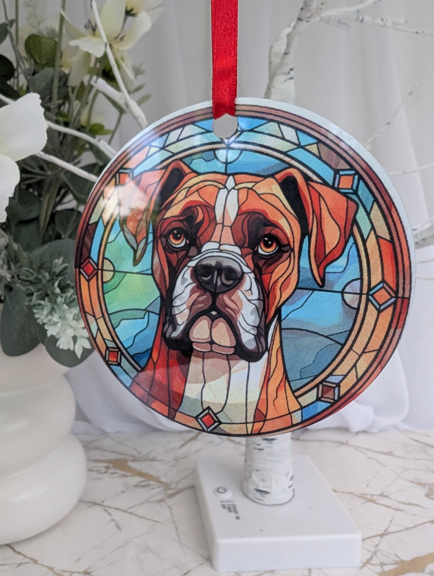 Close up of aluminium hanging ornament, 9cm diameter, printed with a Boxer Dog with blues and brown stained glass style print background.