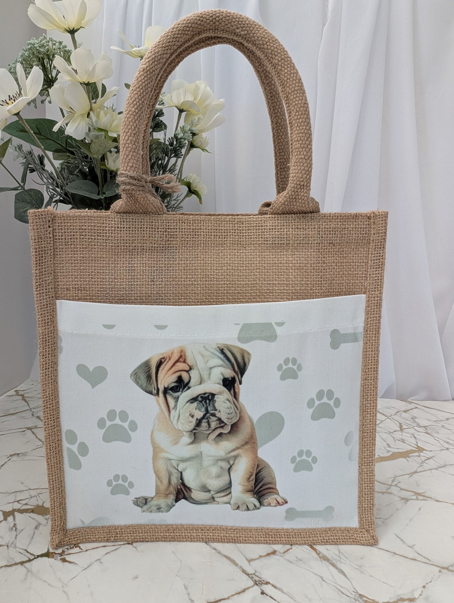 Bulldog tote bag made of sustainably sourced jute. With cream front pocket printed with cute bulldog image against a background of soft grey pawprints hearts and bones