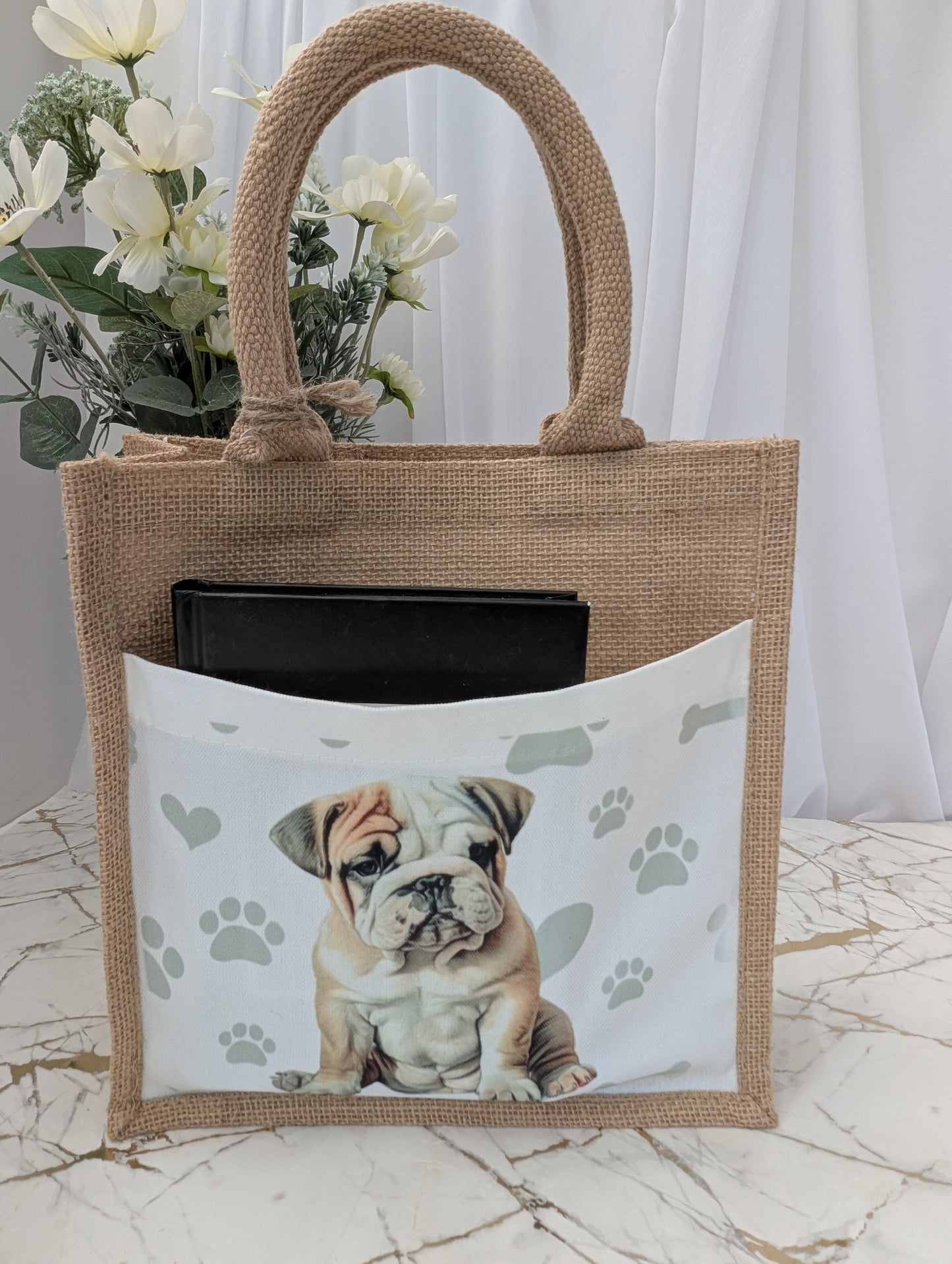 Bulldog tote bag made of sustainably sourced jute. showing cream front pocket with black book in it.