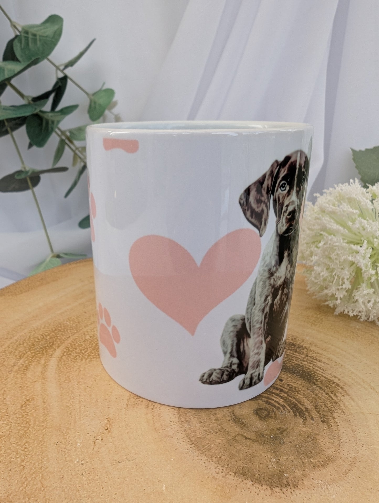 Side View of 11oz white ceramic German Short Haired Pointer Dog Mug with heart, paw and bone background in pink