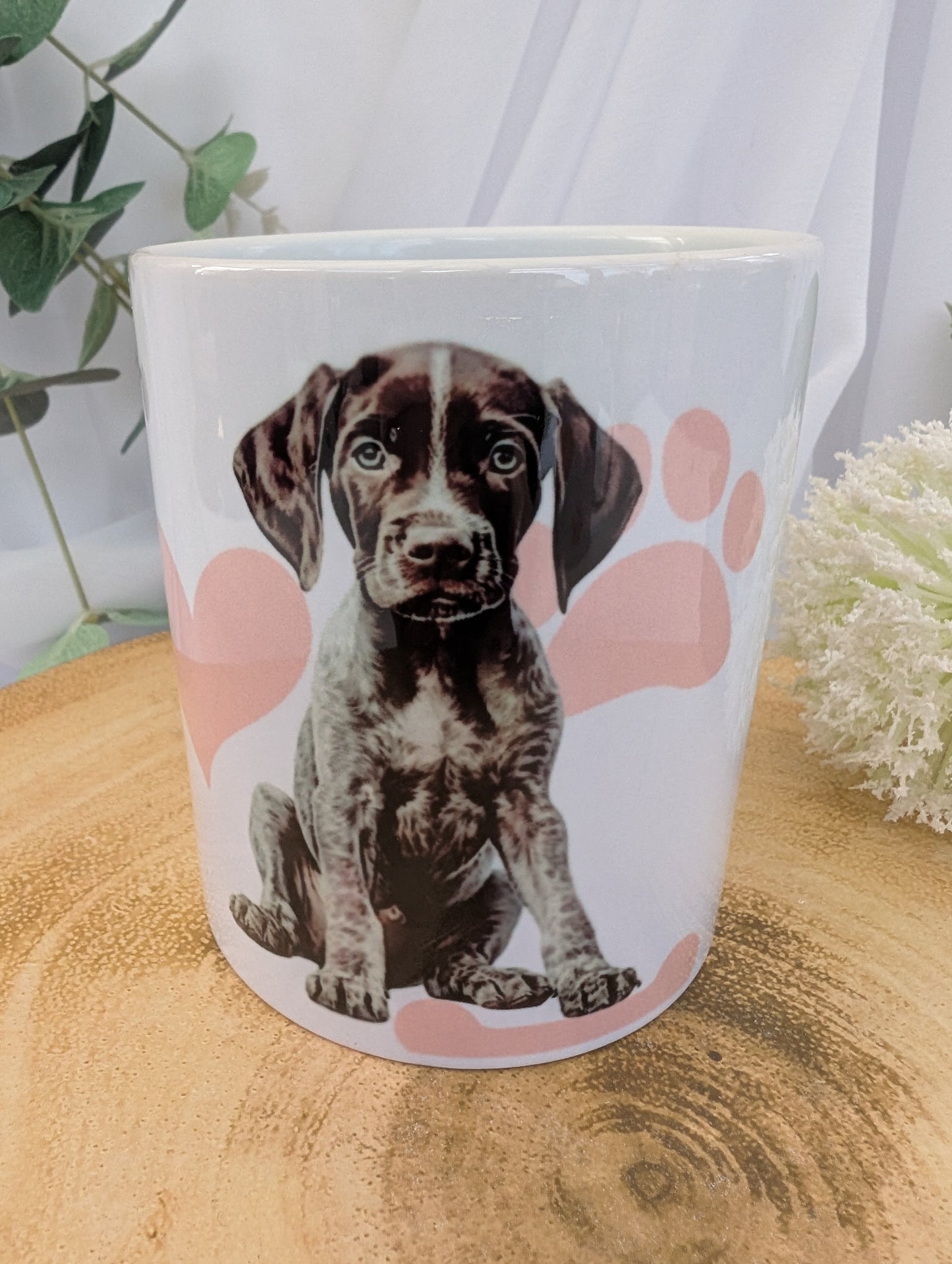 Close up view of 11oz white ceramic German Short Haired Pointer Dog Mug with heart, paw and bone background in pink