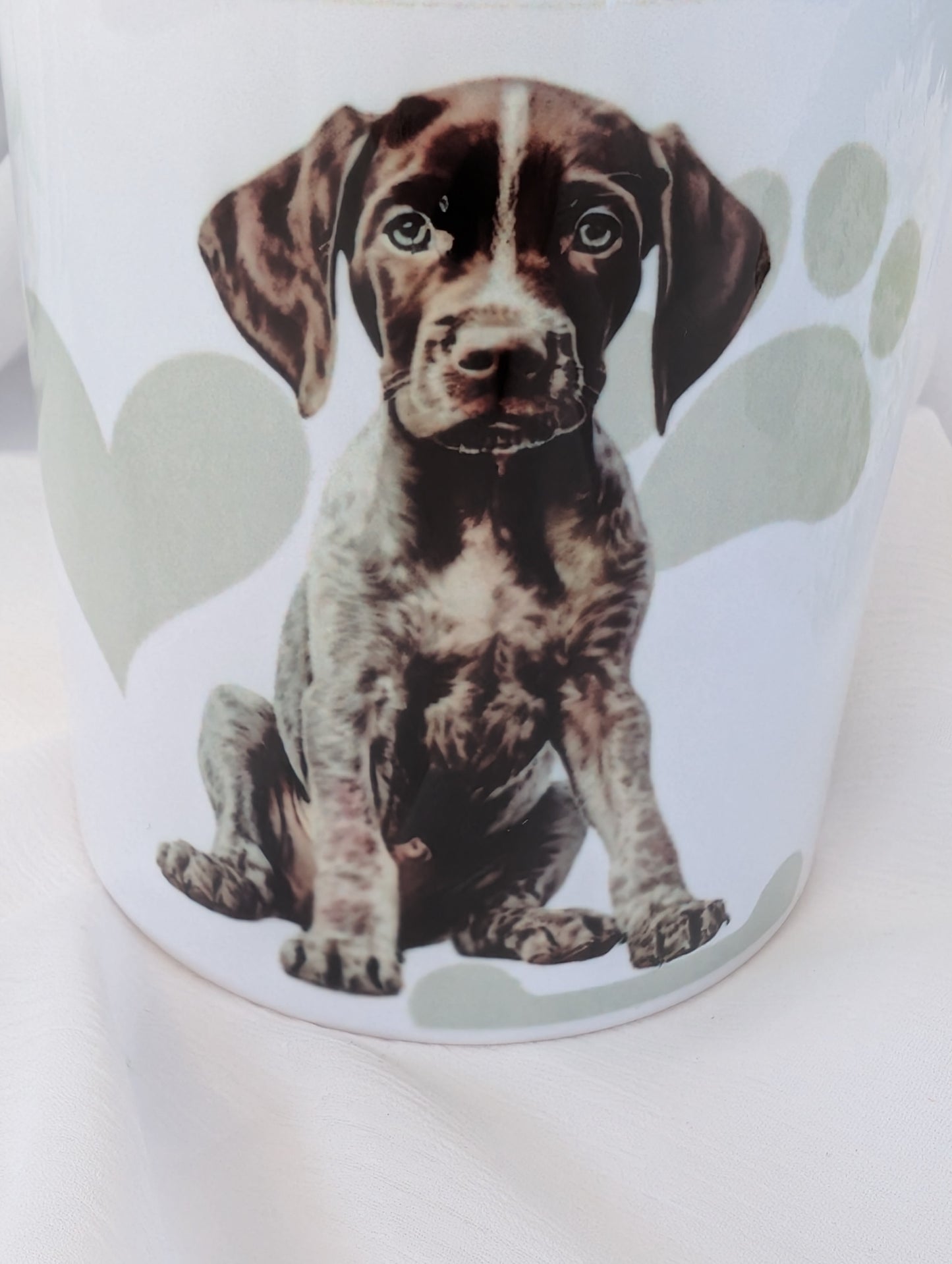 Close up view of 11oz white ceramic German Short Haired Pointer Dog Mug with heart, paw and bone background in grey