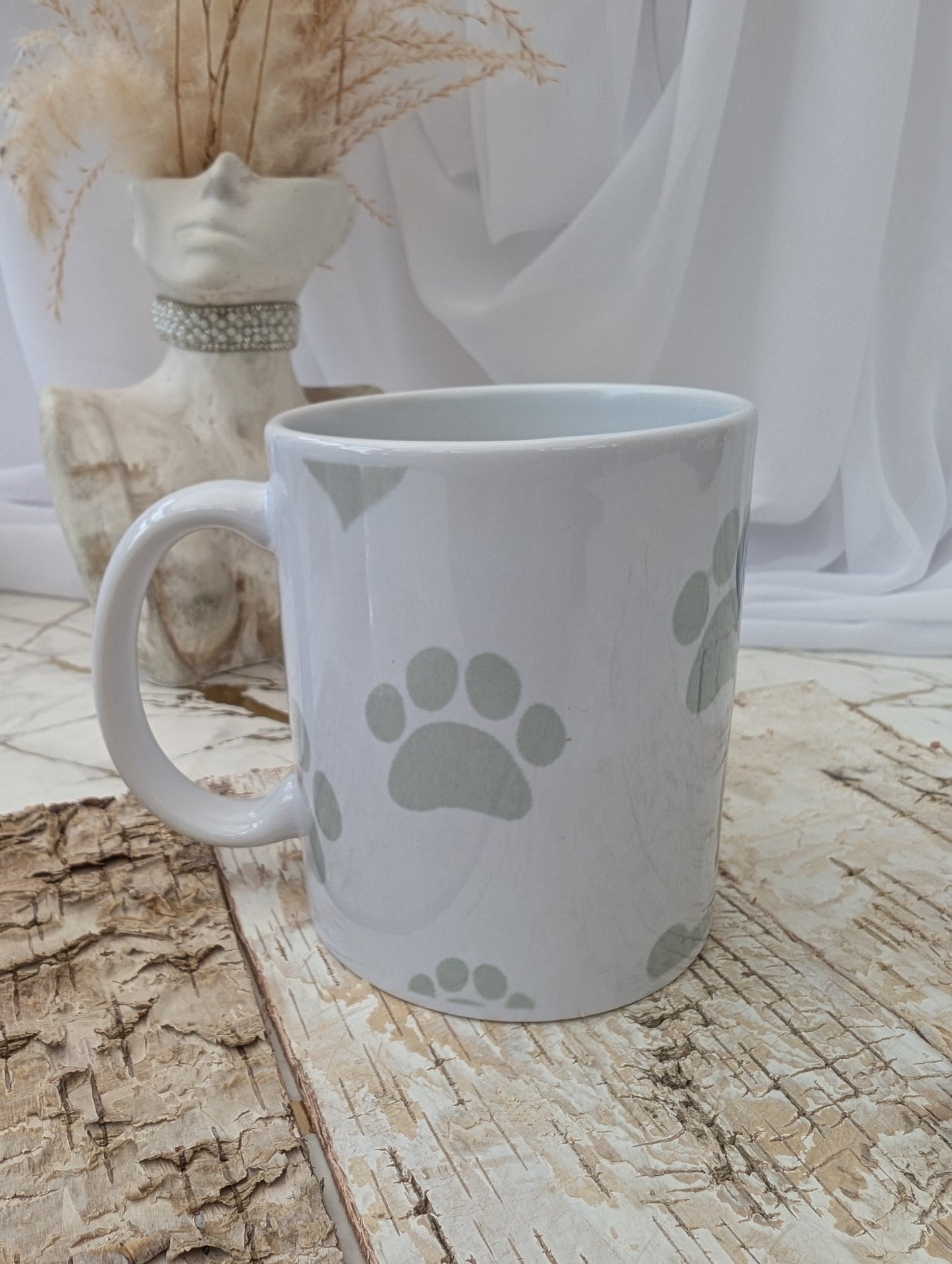 Right side view of white Rottweiler mug with paw prints on a wooden surface