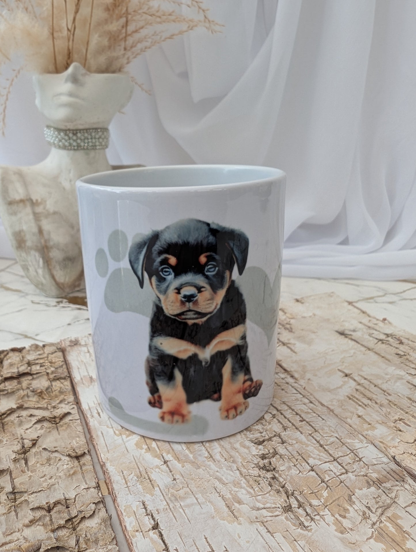 Front view of white Rottweiler mug with paw prints on a wooden surface