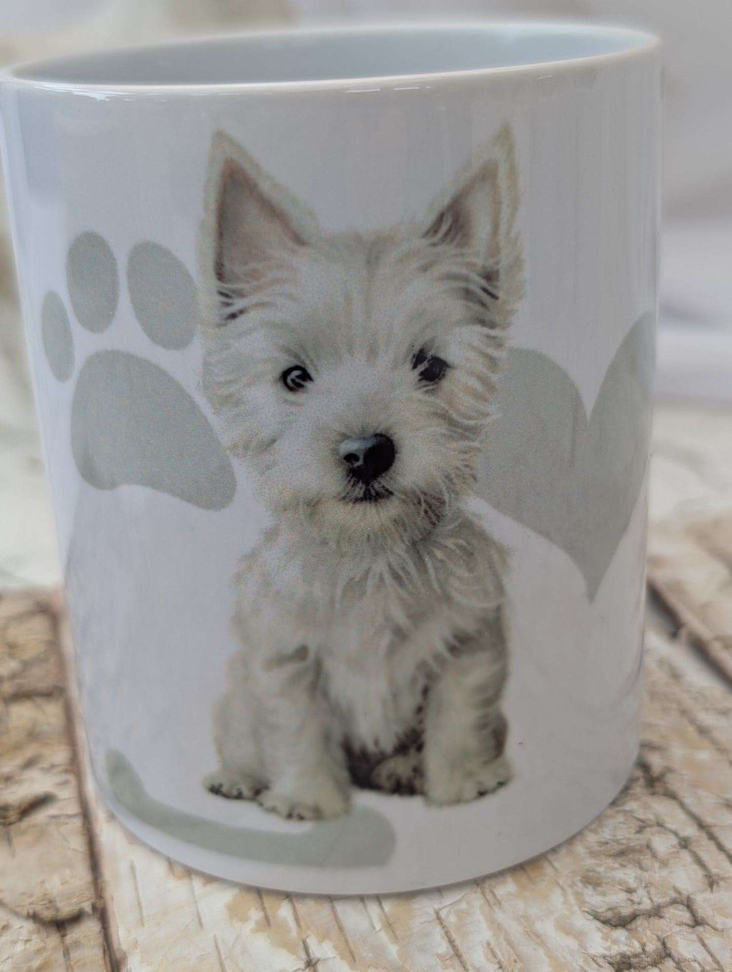 close up of Western Highland Terrier mug with grey paws, heart and bones background