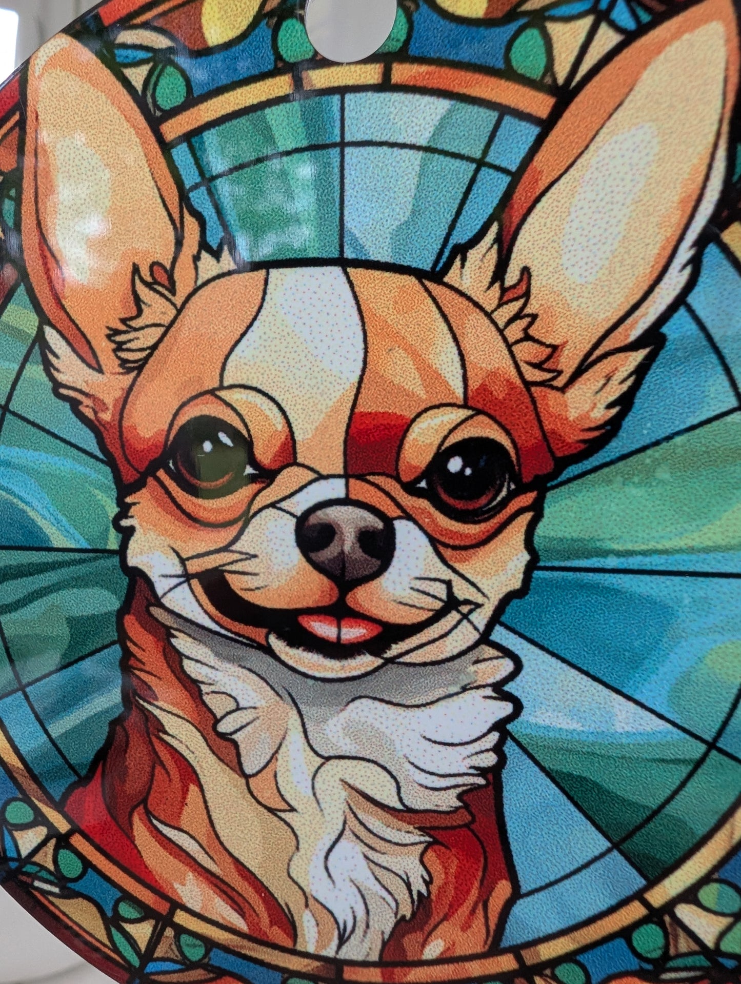 zoom close up of smiling chichuahua stained glass effect hanging ornament using blues yellows and browns. 9cm diameter hanging on a red ribbon