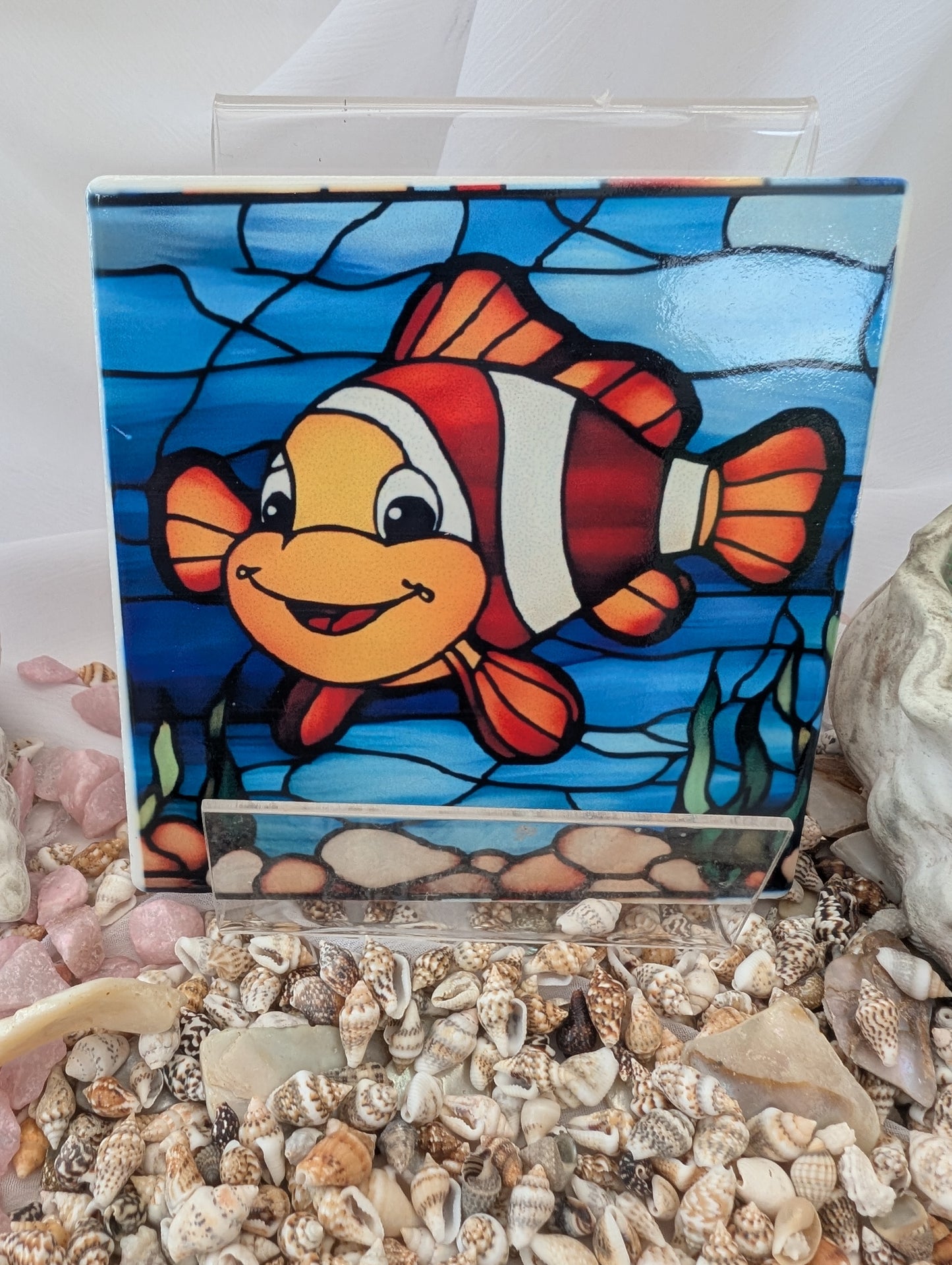Stained glass Clownfish Coaster on a bed of seashells