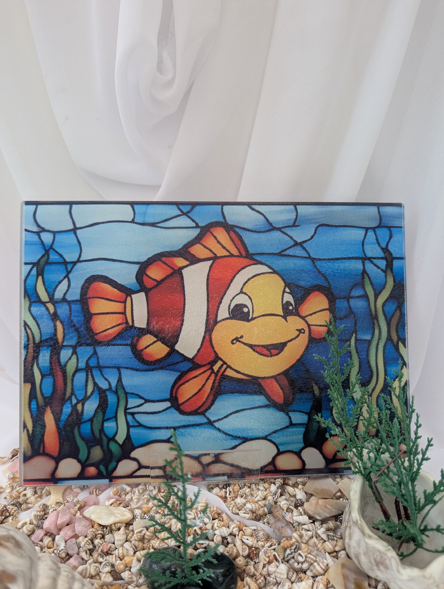 Stained glass panel with a clownfish design on a base of seashells