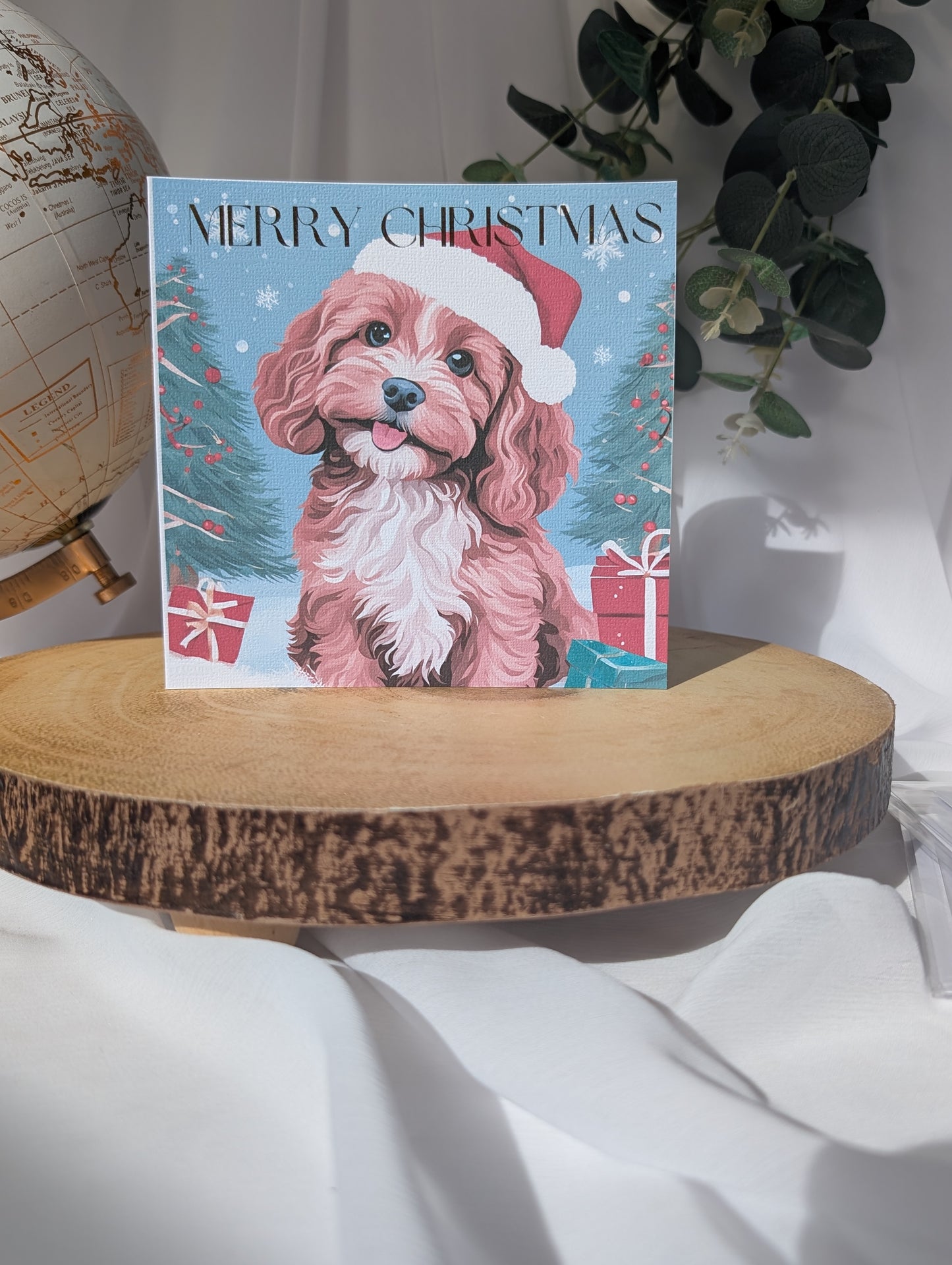 Dog Christmas card with a Cavapoo / Cockapoo wearing a Santa hat on a wooden surface.