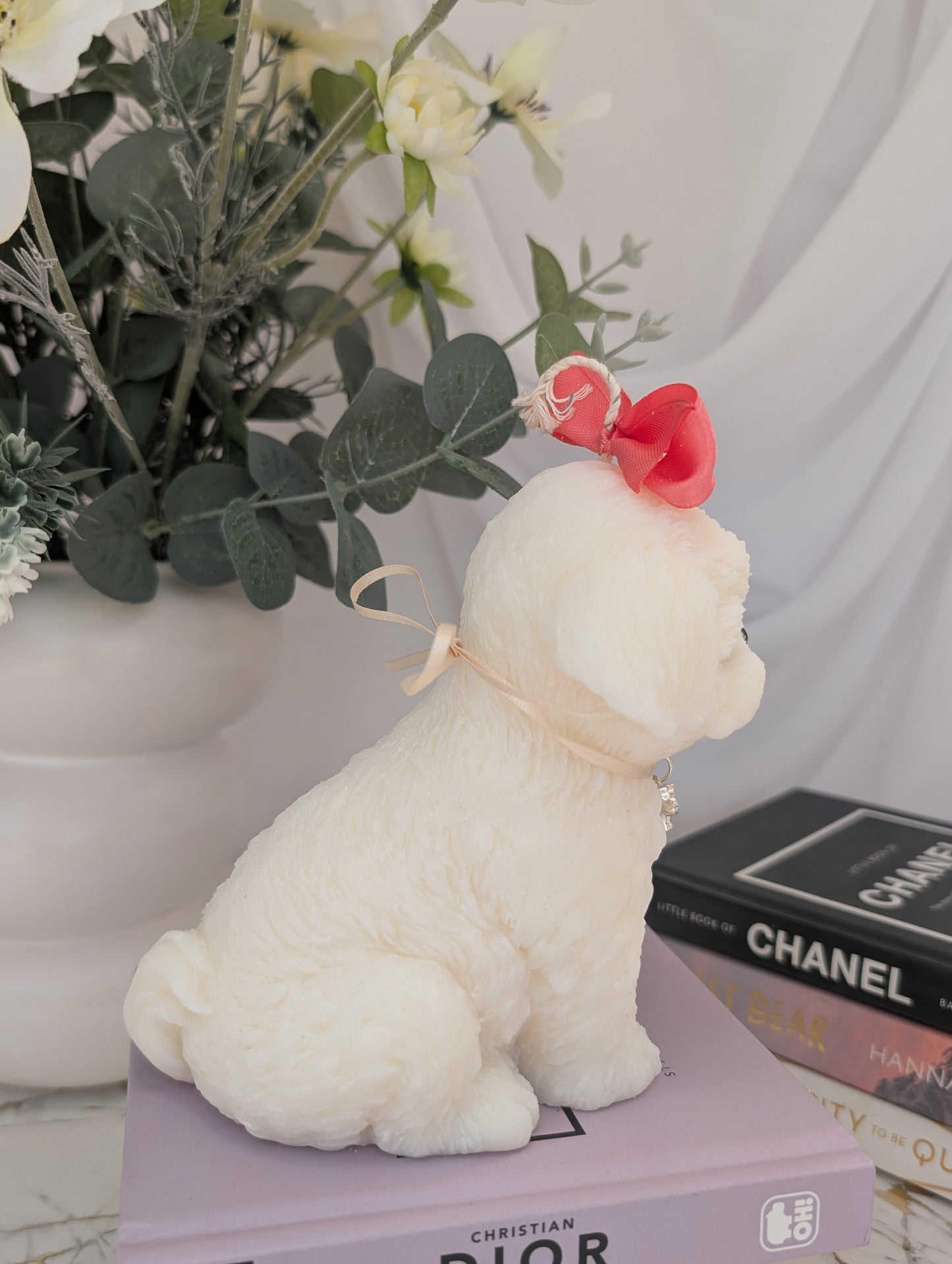 Profile view of dog shaped candle - shih tzu natural colour coconut and rapeseed wax with pink ribbon and removable charm