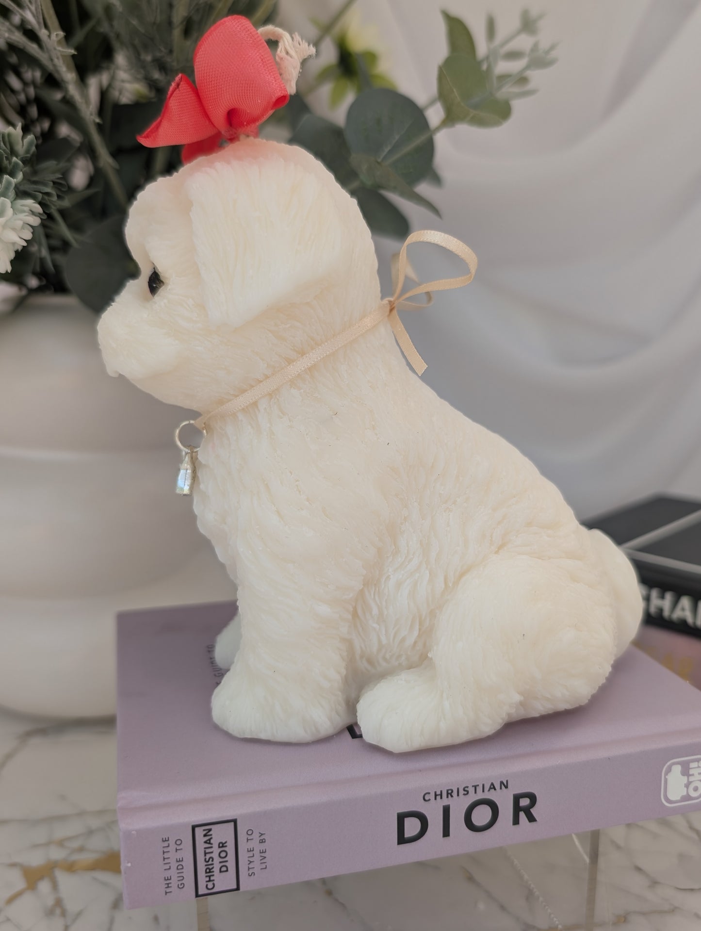 Left side view of dog shaped candle - shih tzu natural colour coconut and rapeseed wax with pink ribbon and removable charm