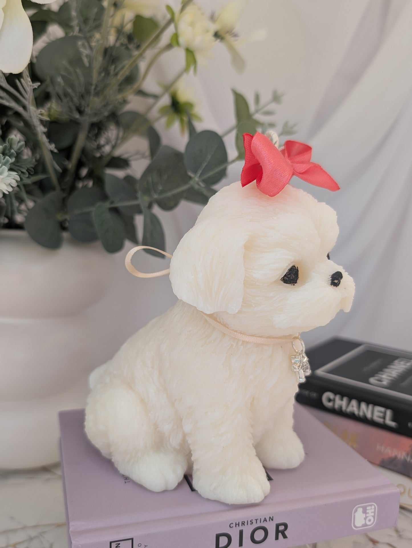 side view of dog shaped candle - shih tzu natural colour coconut and rapeseed wax with pink ribbon and removable charm