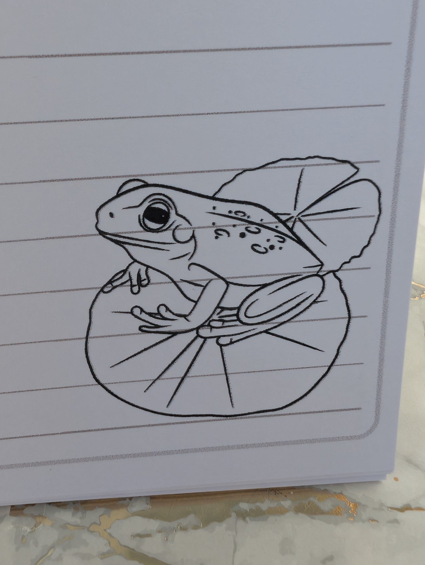 close up of frog on lily pad line drawing printed on bottom left of inside pages of frog notebook