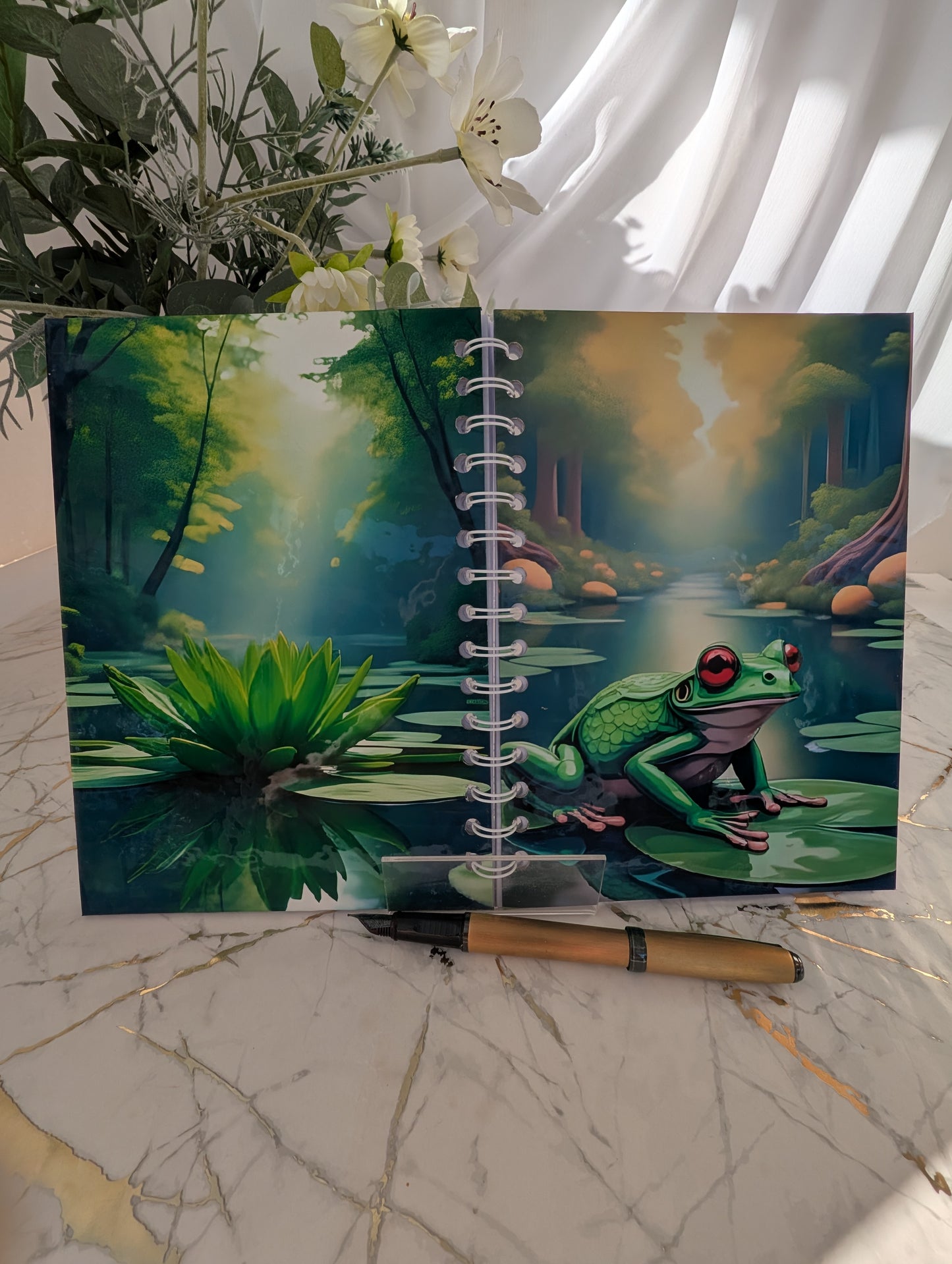 Front and back view of a handmade, glossy hardback cover notebook, featuring a colourful frog on a lilypad design