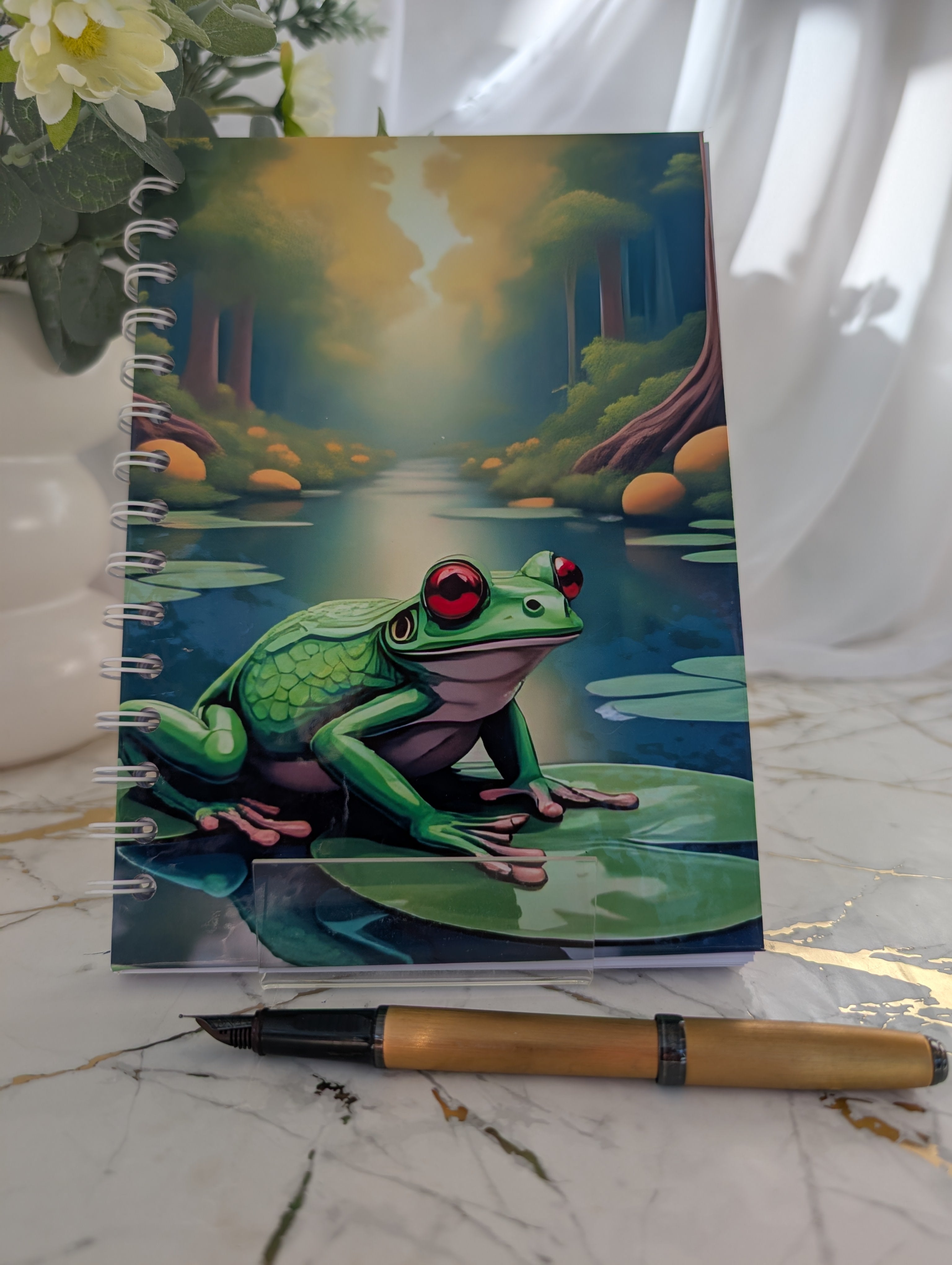 Frog Gift - Front view of a handmade, glossy hardback cover notebook, featuring a colourful frog on a lilypad design