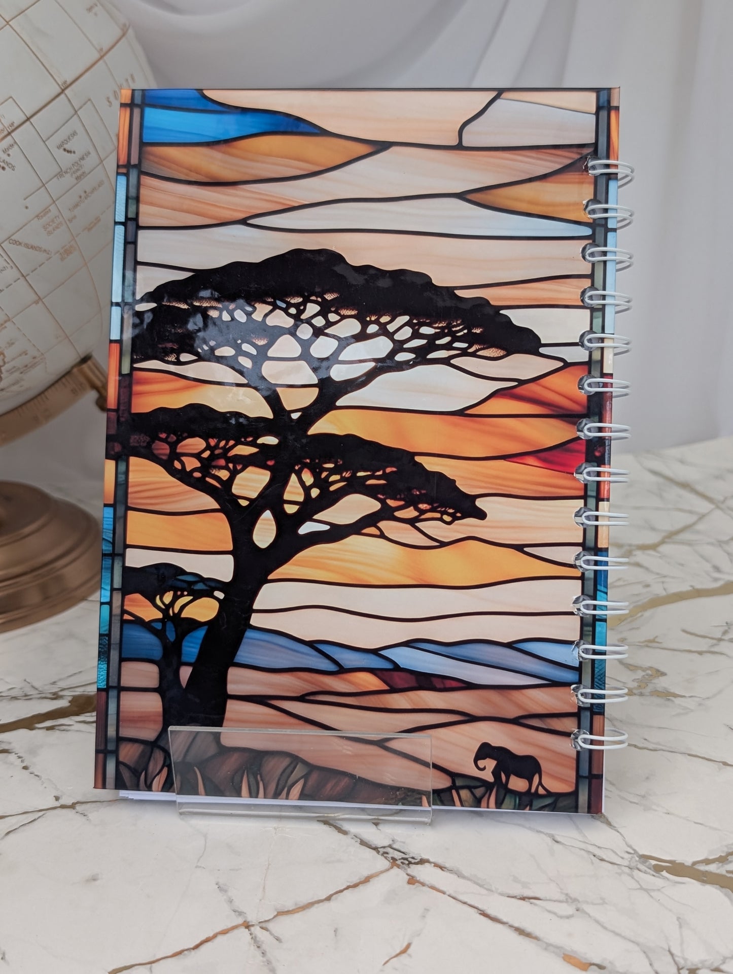 Back cover of stained glass style Giraffe spiral bound notebook - showing image of African savannah and acacia trees.