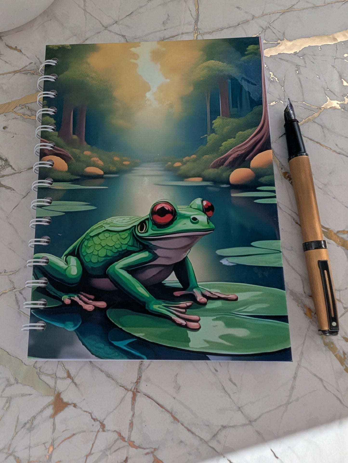 Close up of a handmade, glossy hardback cover notebook, featuring a colourful frog on a lilypad design