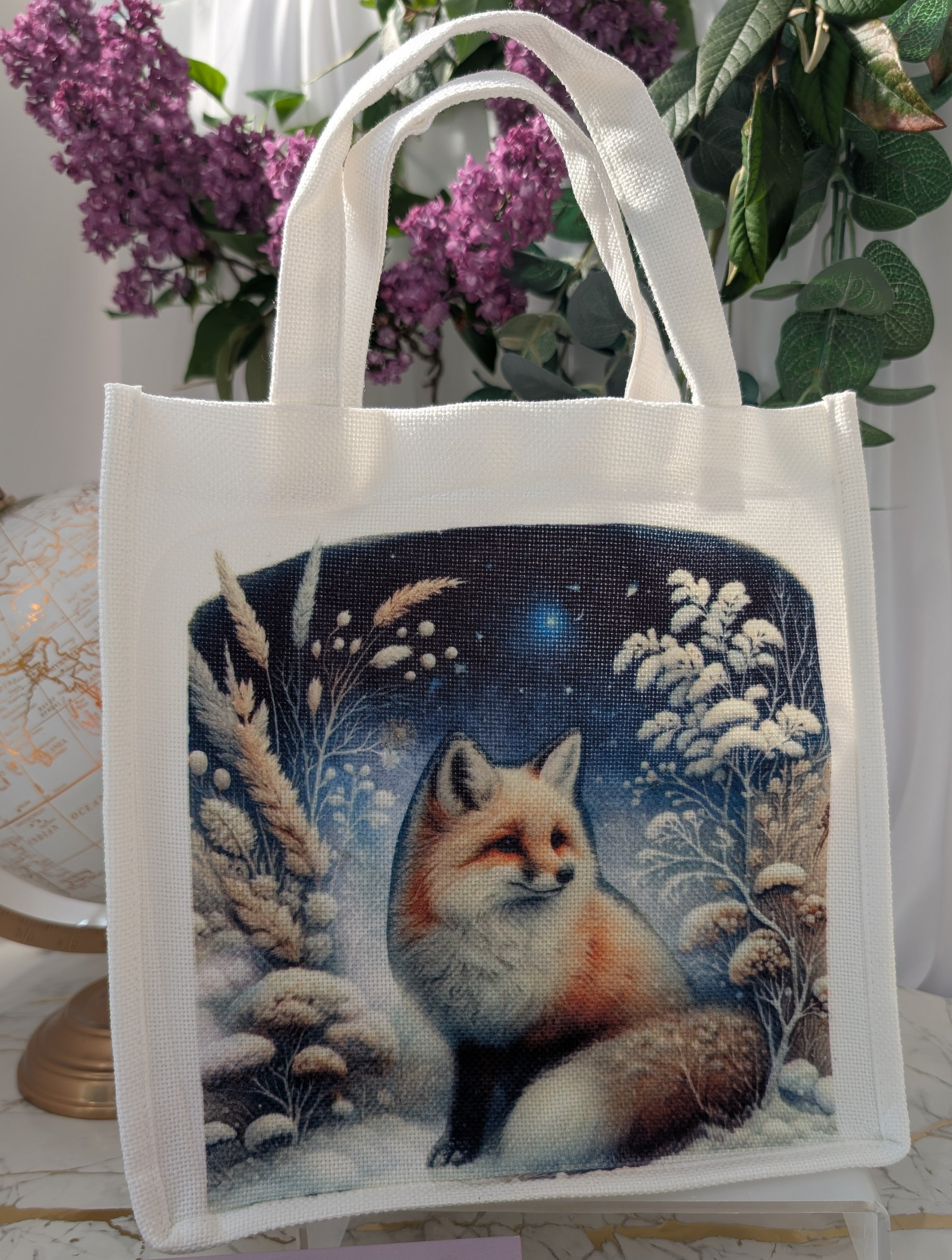 white linen totebag showing image of a sitting fox at night against a background of foliage covered in snow