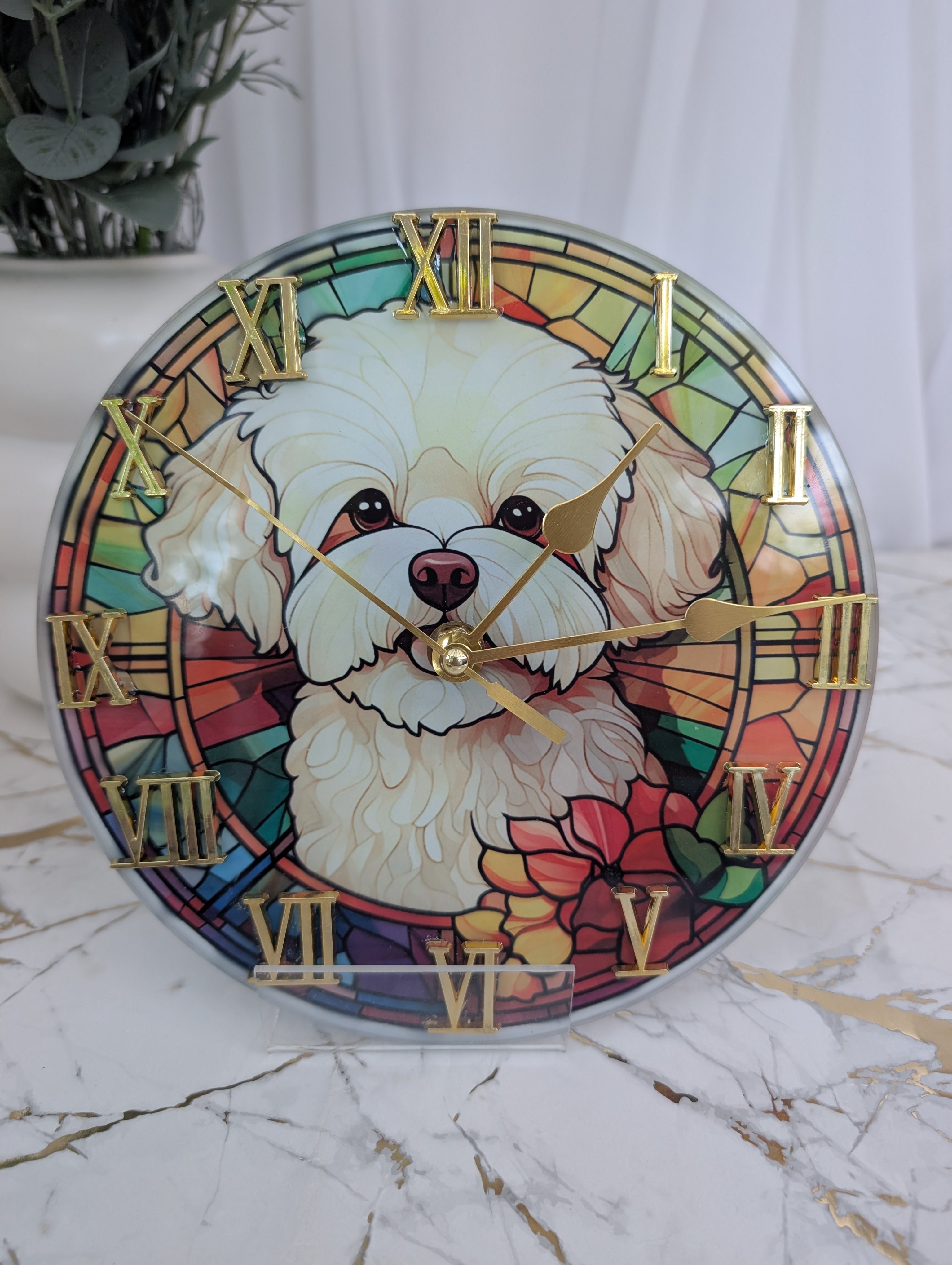 Multi colour stained glass style wallclock.  20cm diameter with gold Roman numerals and image of a white Maltese Terrier