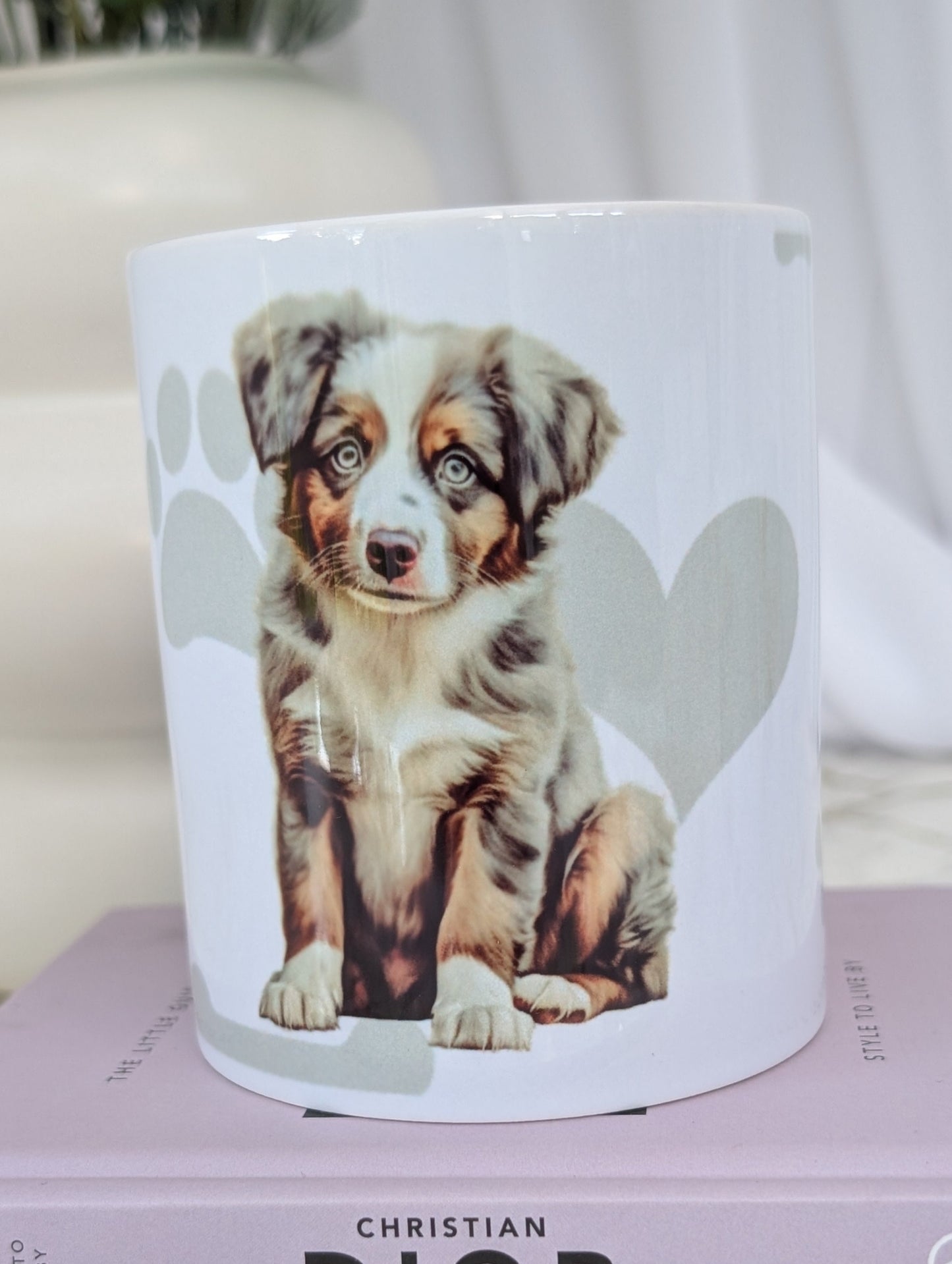 White ceramic dishwasher proof mug with watercolour style image of Australian Shepherd puppy against a background of soft grey hearts, pawprints and bones