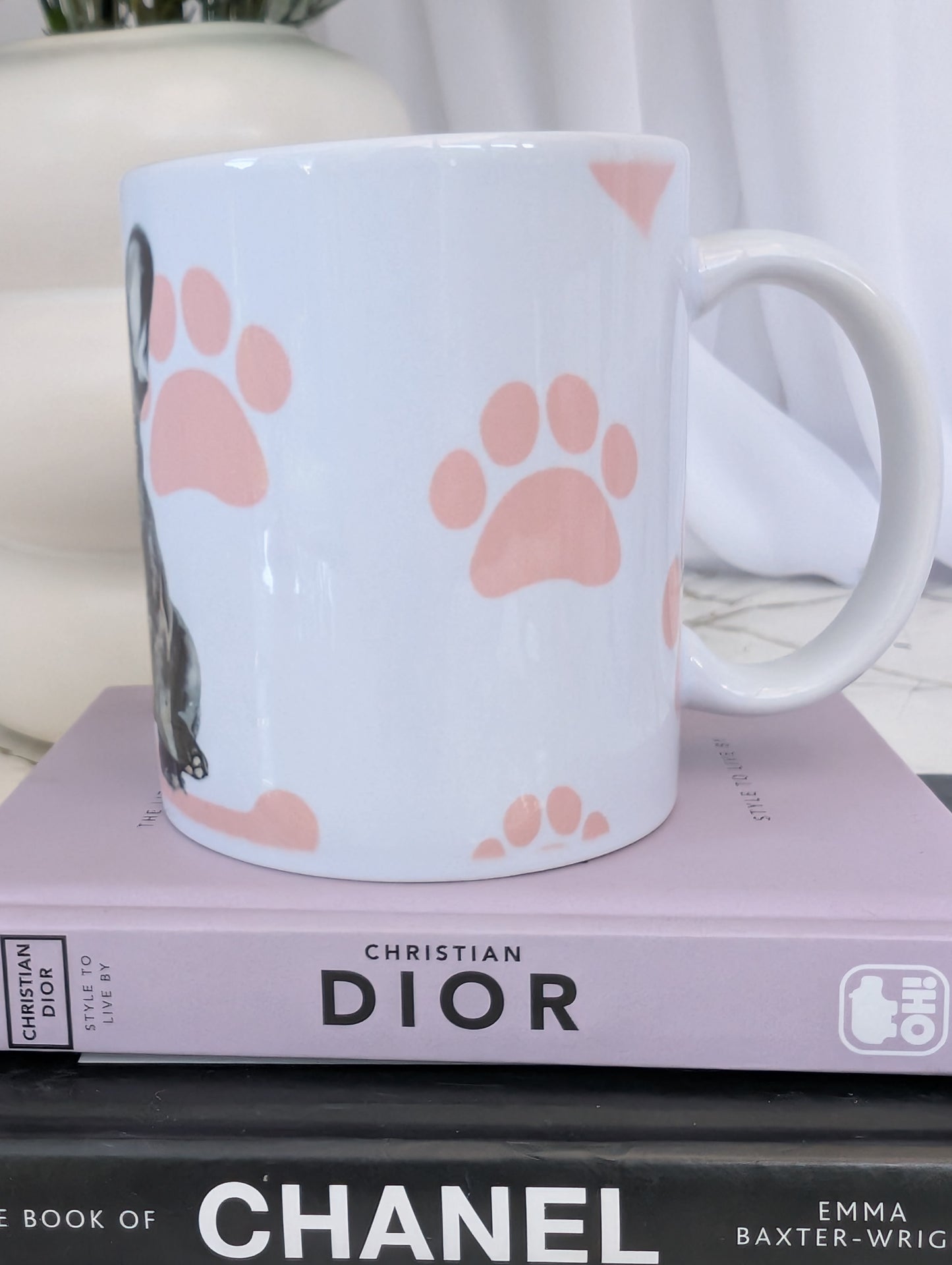 Left side view of white ceramic 11oz French Bulldog mug on a background of pink hearts, paws and bones