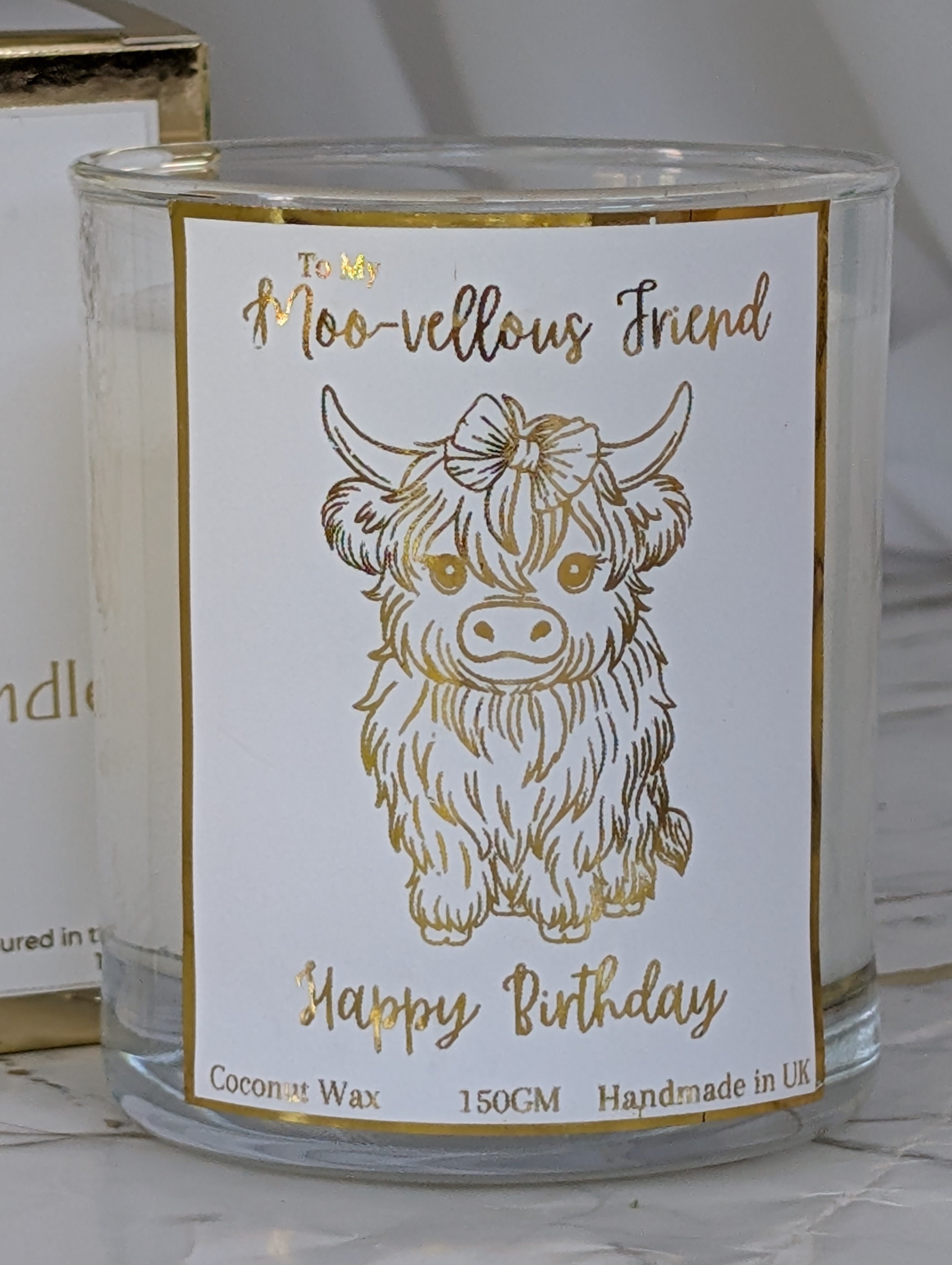 Clear glass container candle with gold foiled label showing an image of a cute highland cow line drawing and text To my Moo-vellous Friend - Happy Birthday