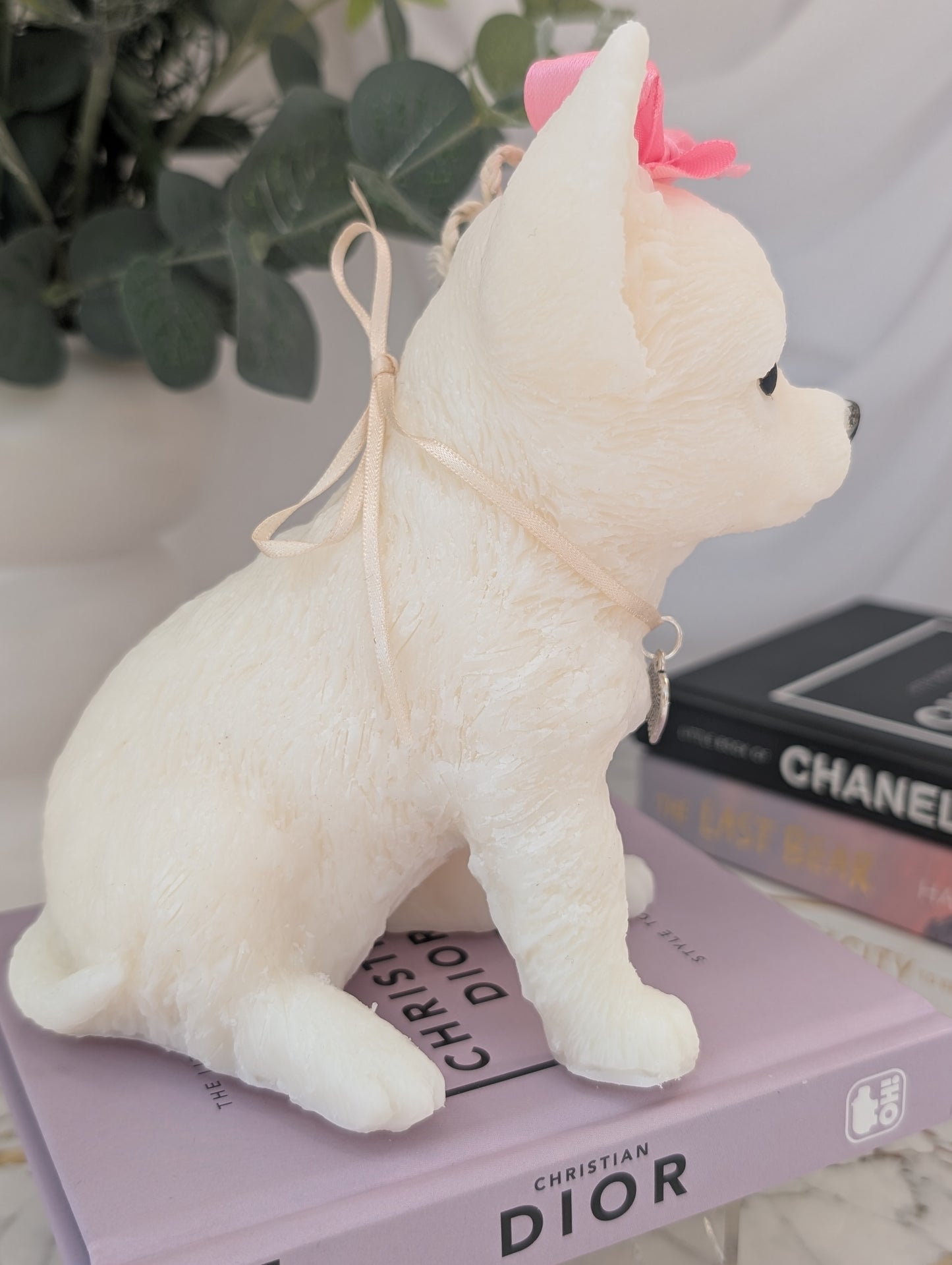 Right-side view of realistic wax Chihuahua candle showing elegant detailing in face and posture, with charm embellishments around neck and head.