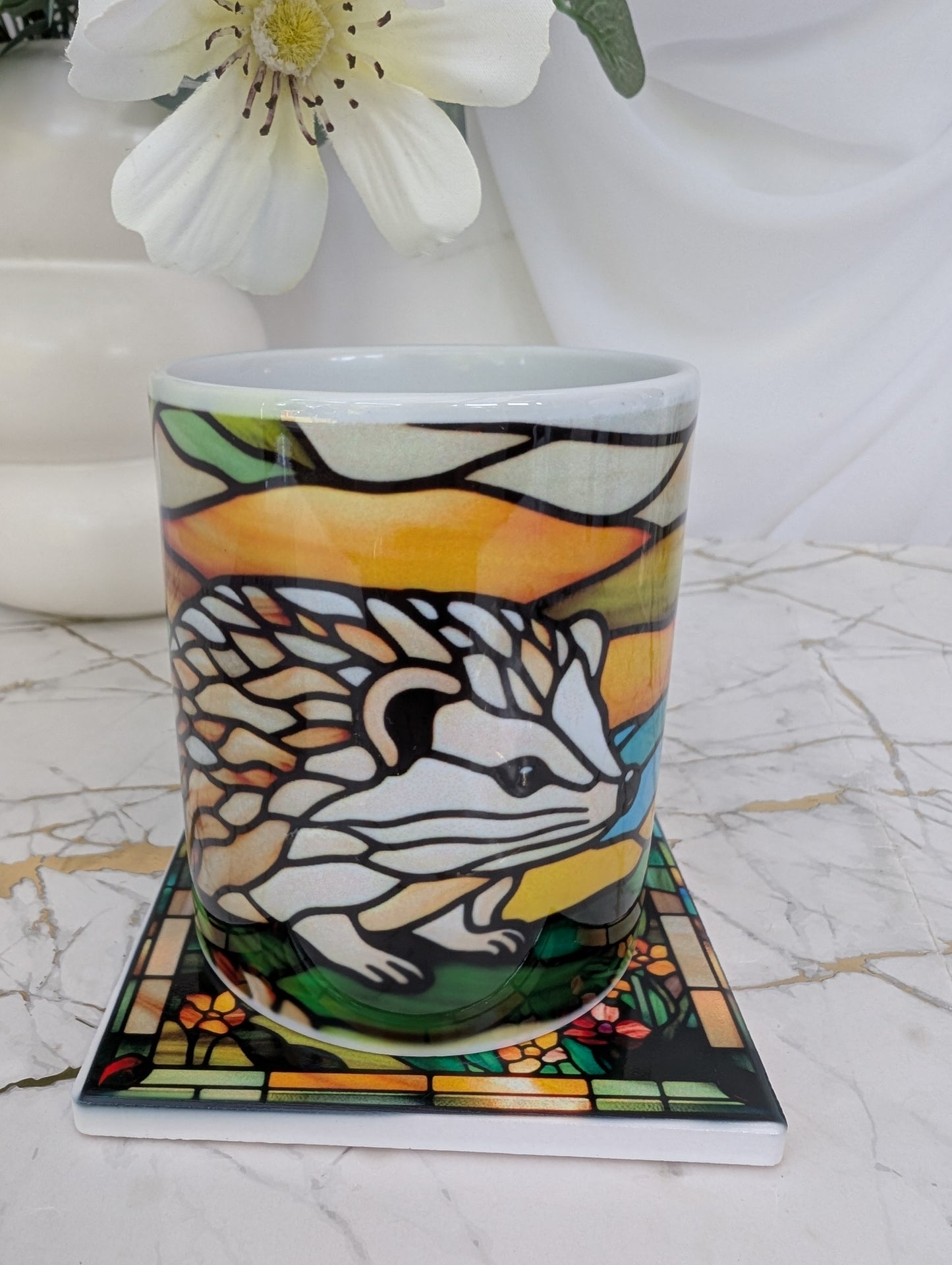 close up of ceramic hedgehog mug on top of hedgehog coaster. The perfect gift for hedgehog lovers, this is 9cm square and stained glass effect
