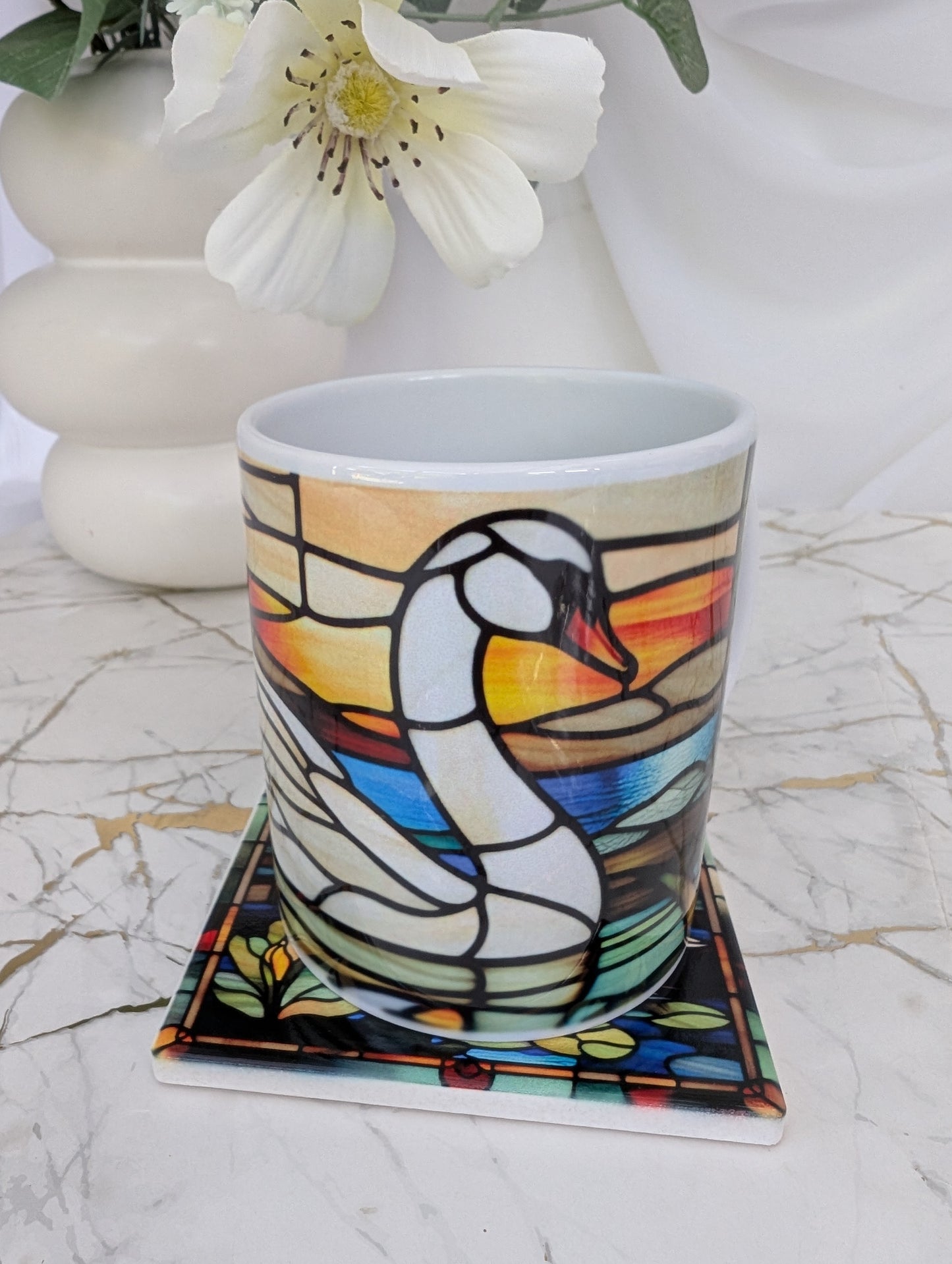 front view of a square swan stained glass effect mug on top of a ceramic coaster