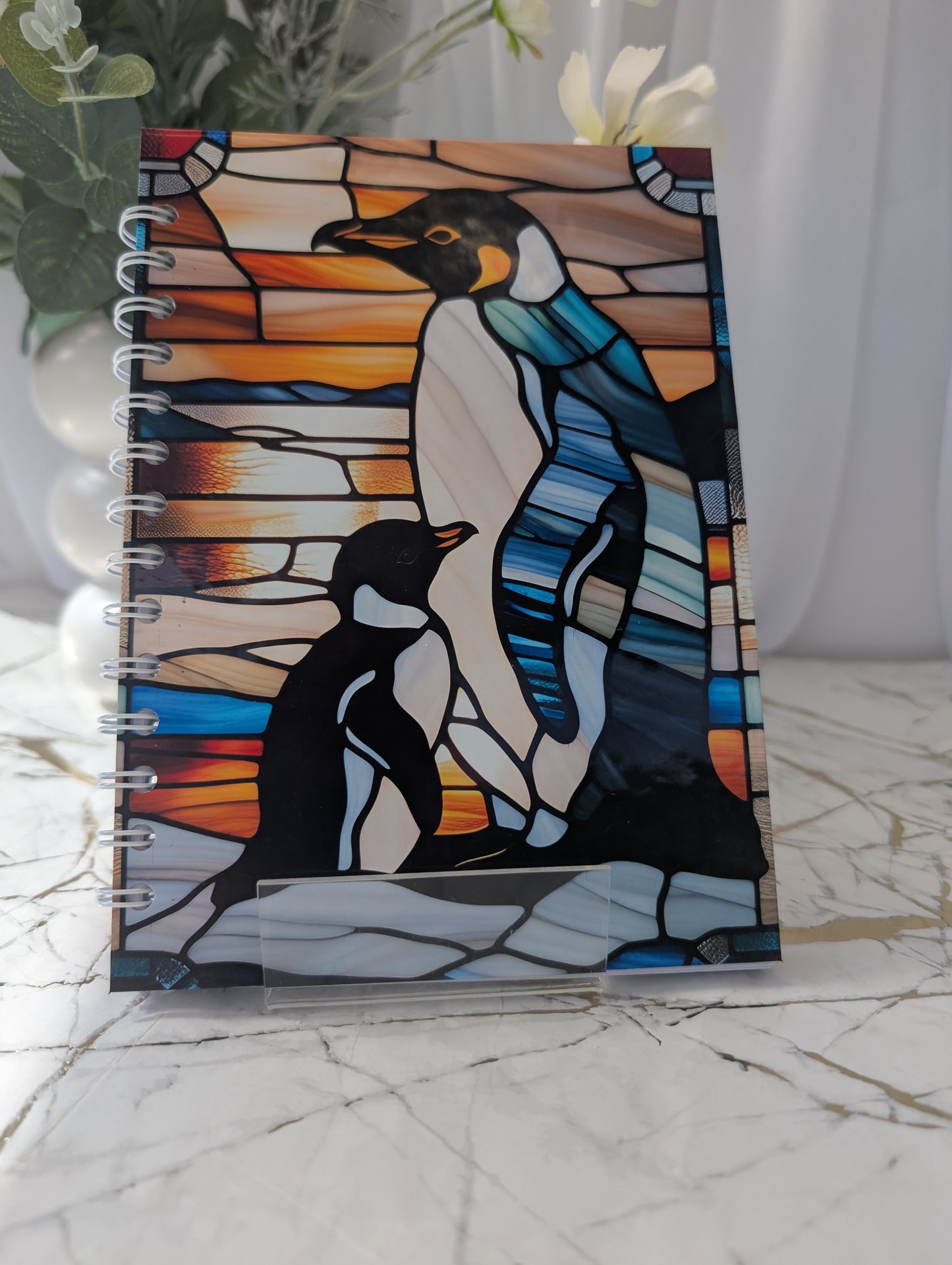 Penguin Gift - Front Cover of notebook with penguin illustration in stained glass style on a marble surface