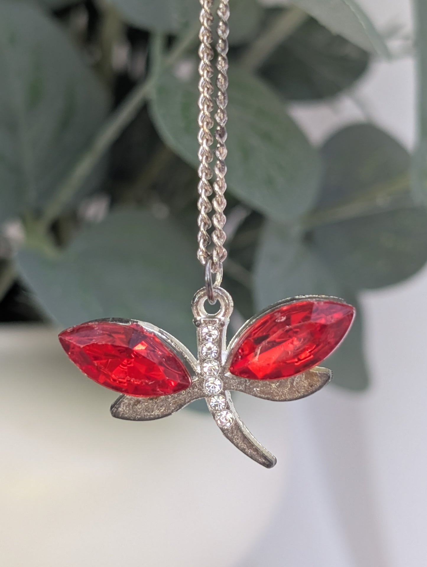 Front view of silver tone dragonfly pendant with red crystal stone wings and clear diamante stone accents