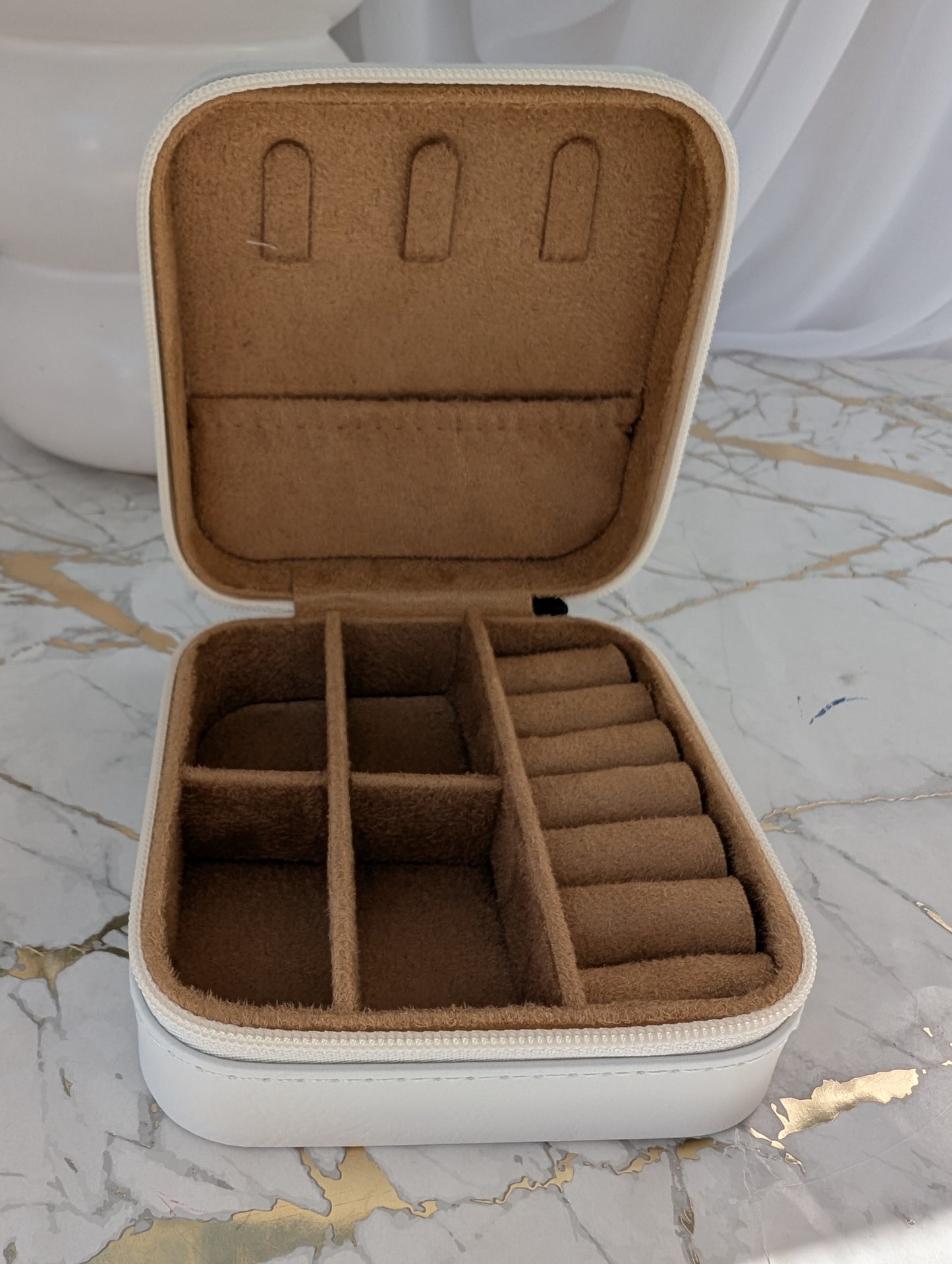 Travel Jewellery Box with brown interior on a marble surface