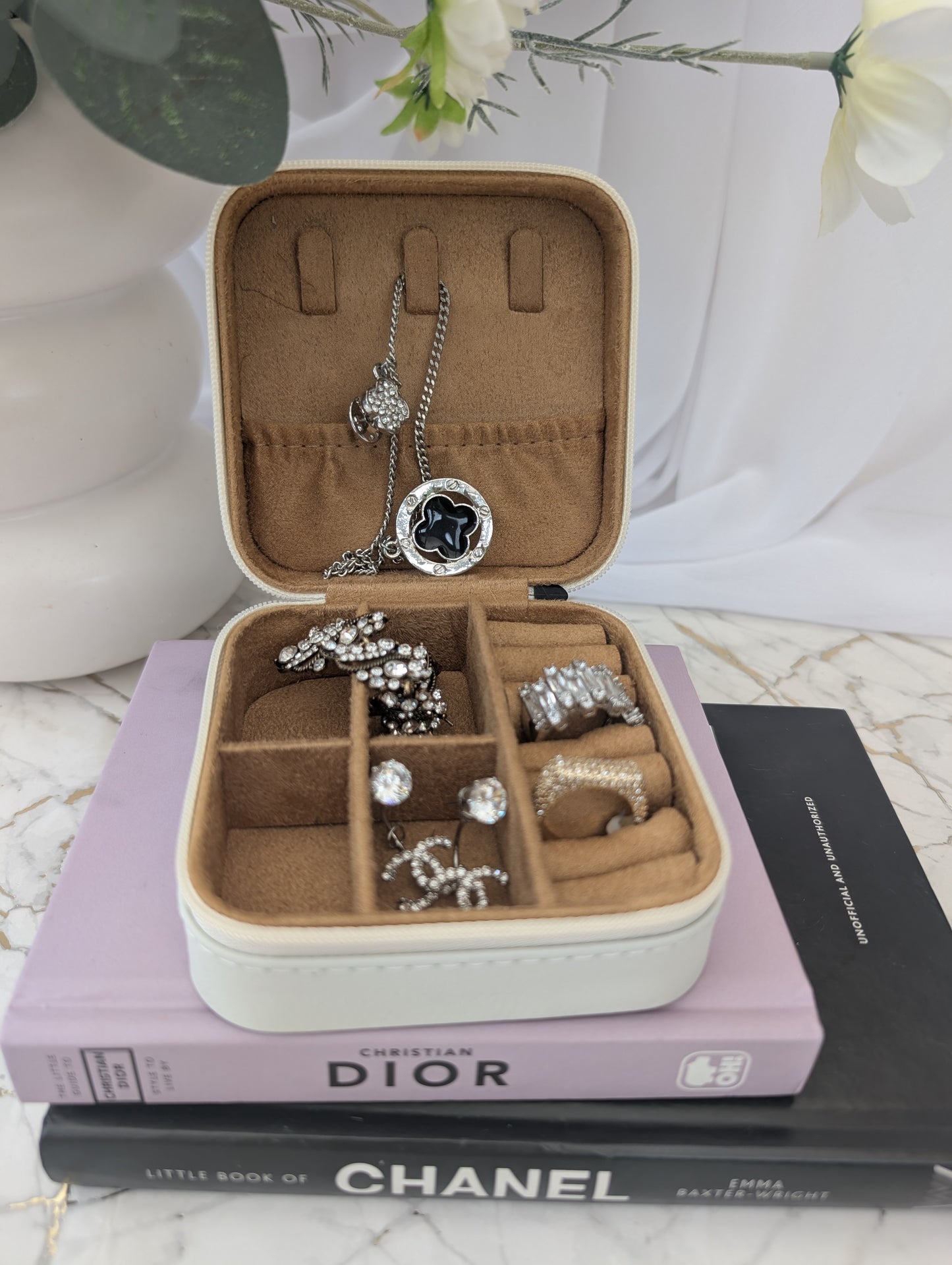 Travel Jewellery box with jewellery on top of Chanel and Dior books