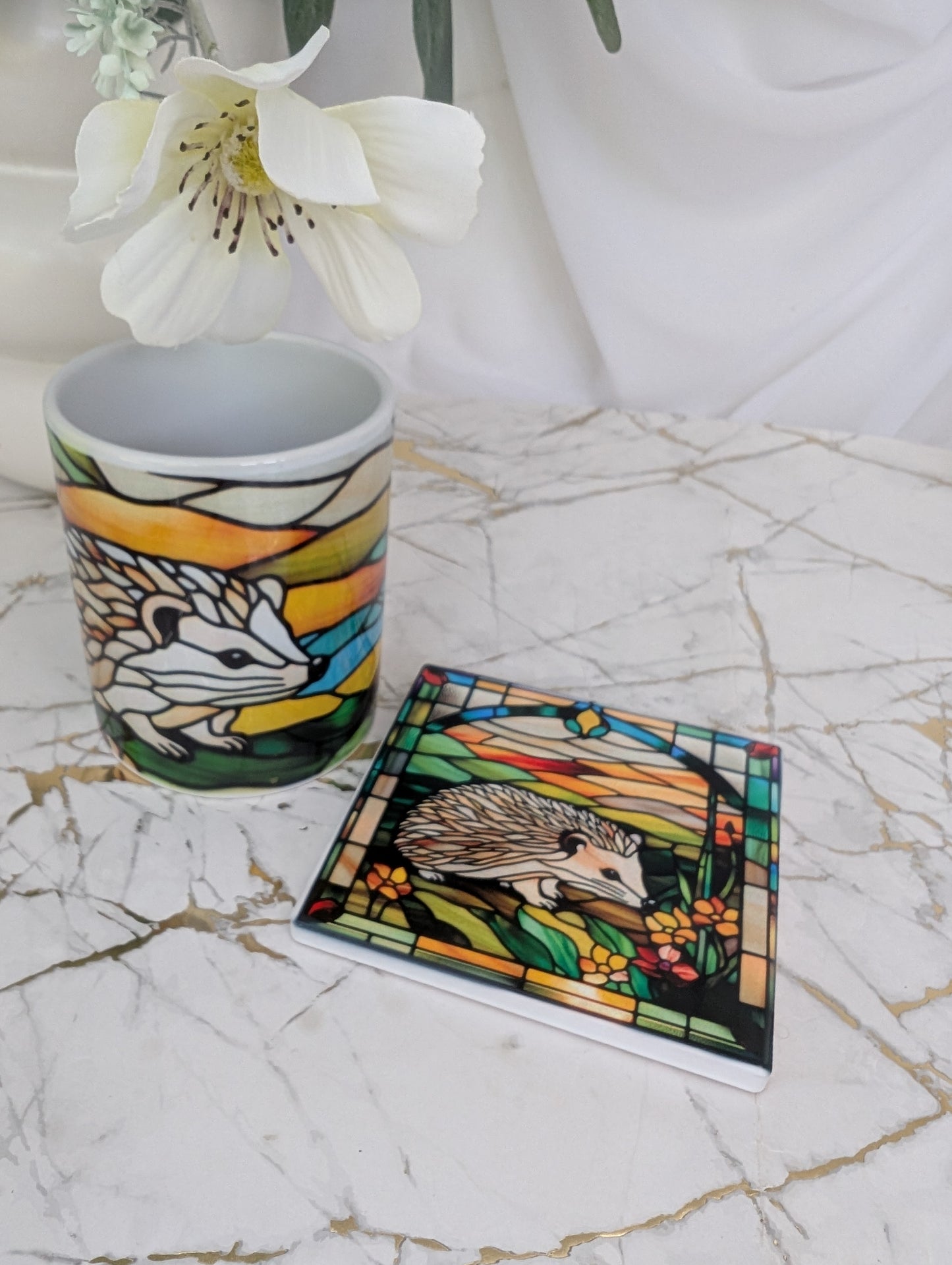 Top view of ceramic hedgehog coaster with matching ceramic mug in the background. The perfect gift for hedgehog lovers, this is 9cm square and stained glass effect design