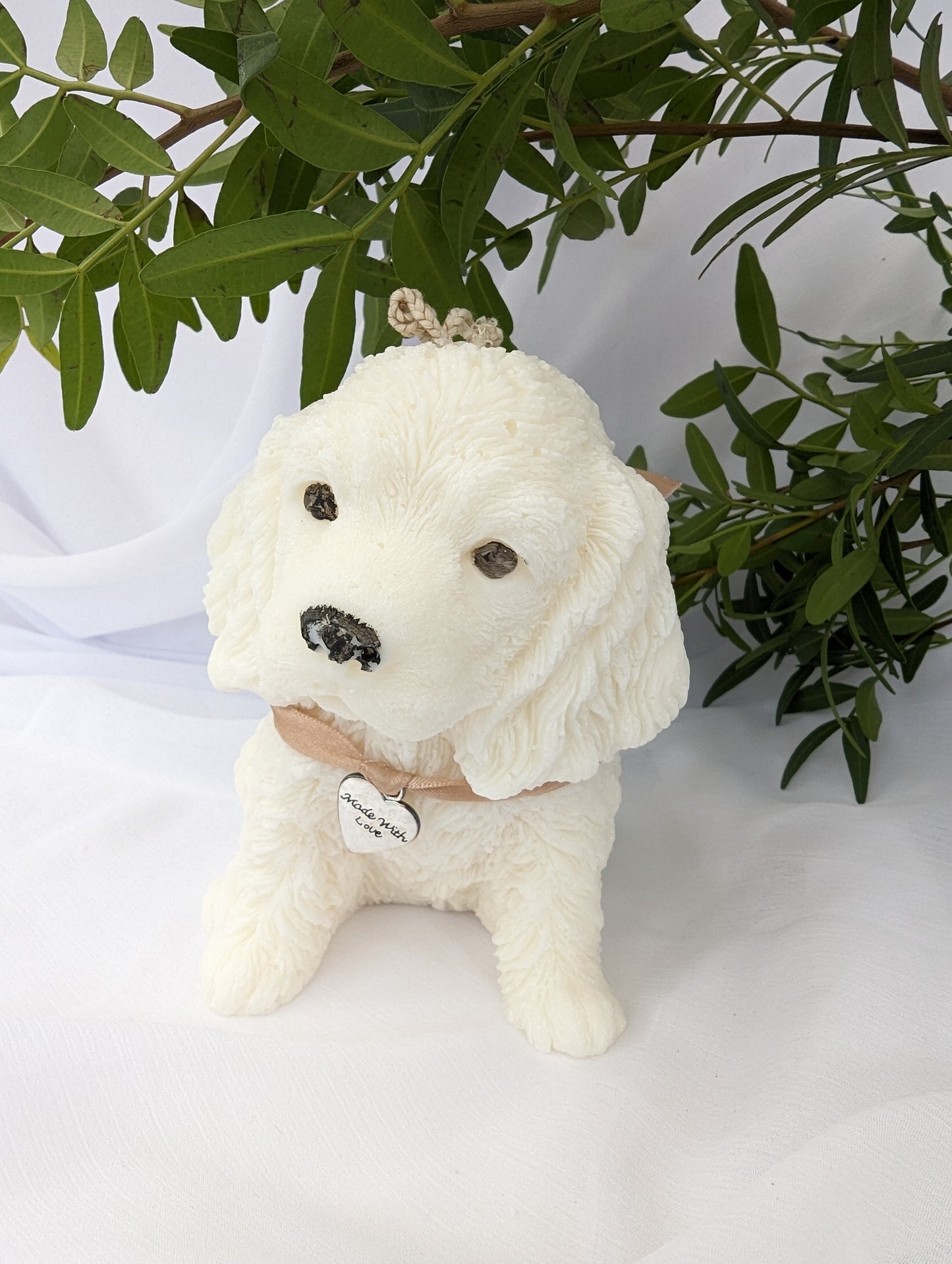 Side view of moulded cocker spaniel puppy candle with ribbon and charm detail around neck