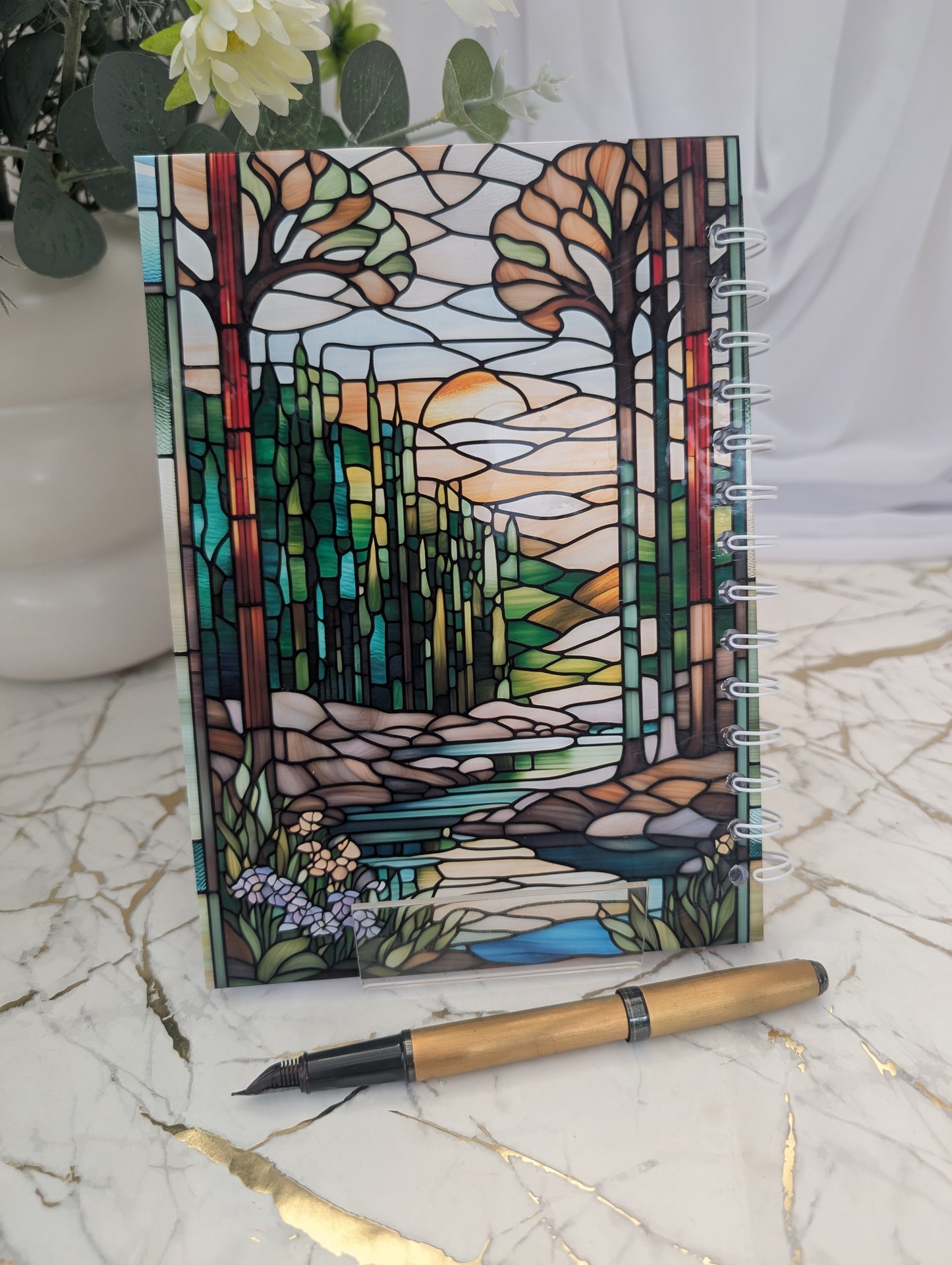 Back cover of stained glass style hedgehog notebook. Showing forest with stream running through it. Beautiful gift for hedgehog lovers