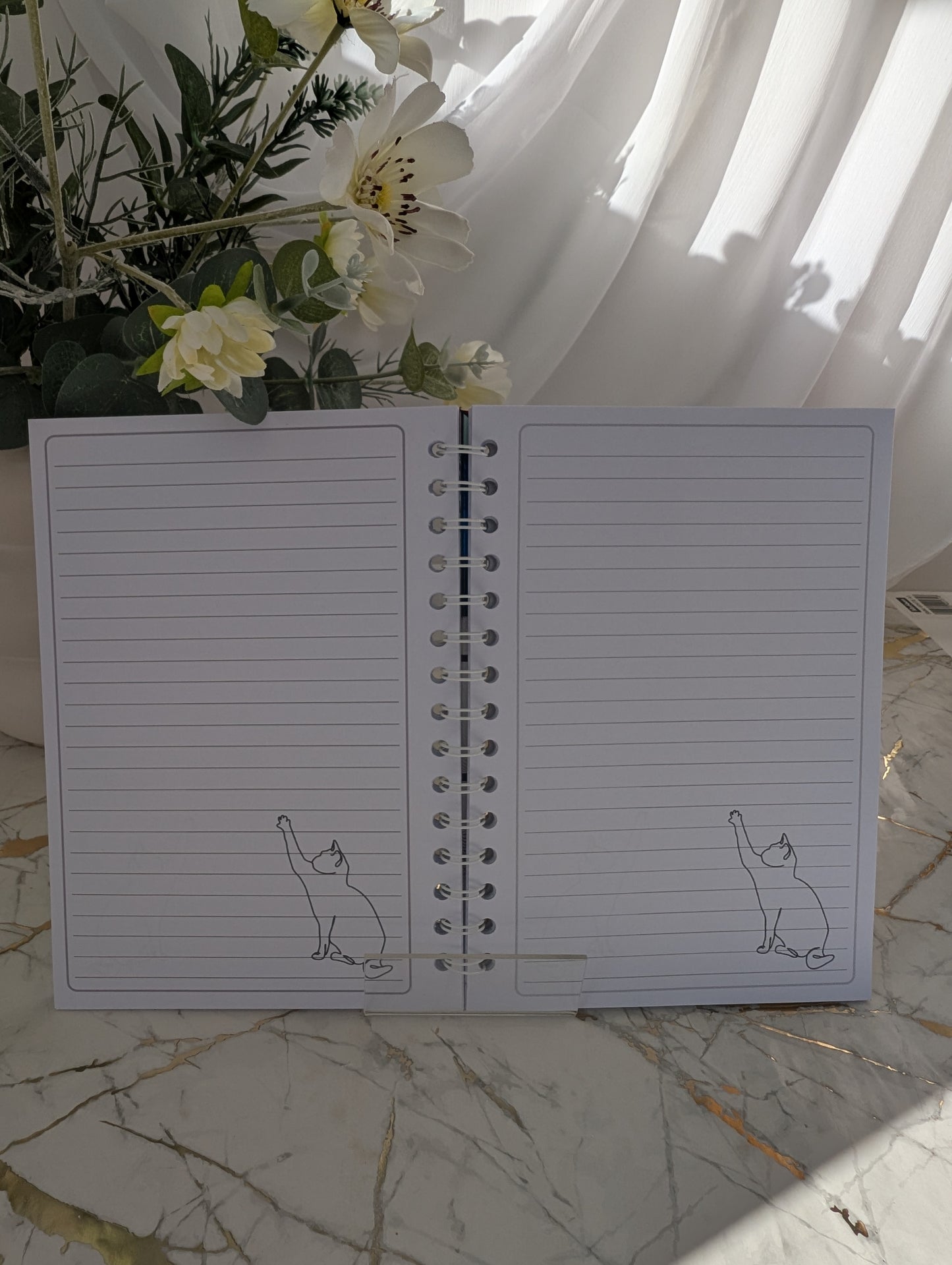 inside pages of stained glass kitten notebook. white lined 120gsm with kitten line drawing in bottom right corner of each page