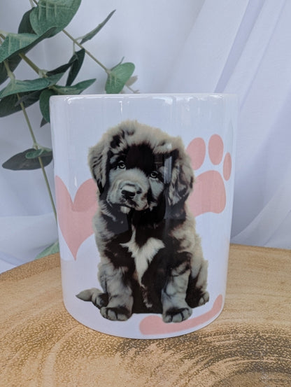 White ceramic mug with cute newfoundland puppy design on a background of pink paws, hearts and bones