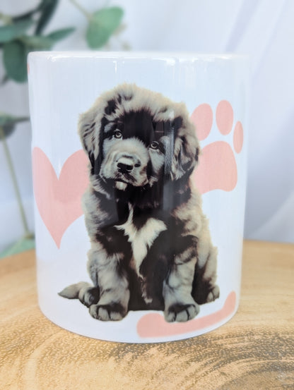 close up of white ceramic mug with cute newfoundland puppy design on a background of pink paws, hearts and bones