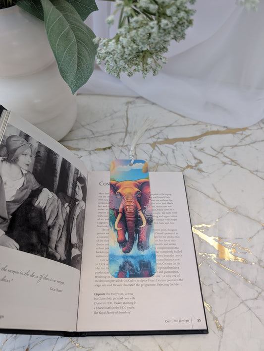 Colorful elephant bookmark on an open book with a vase and flowers in the background