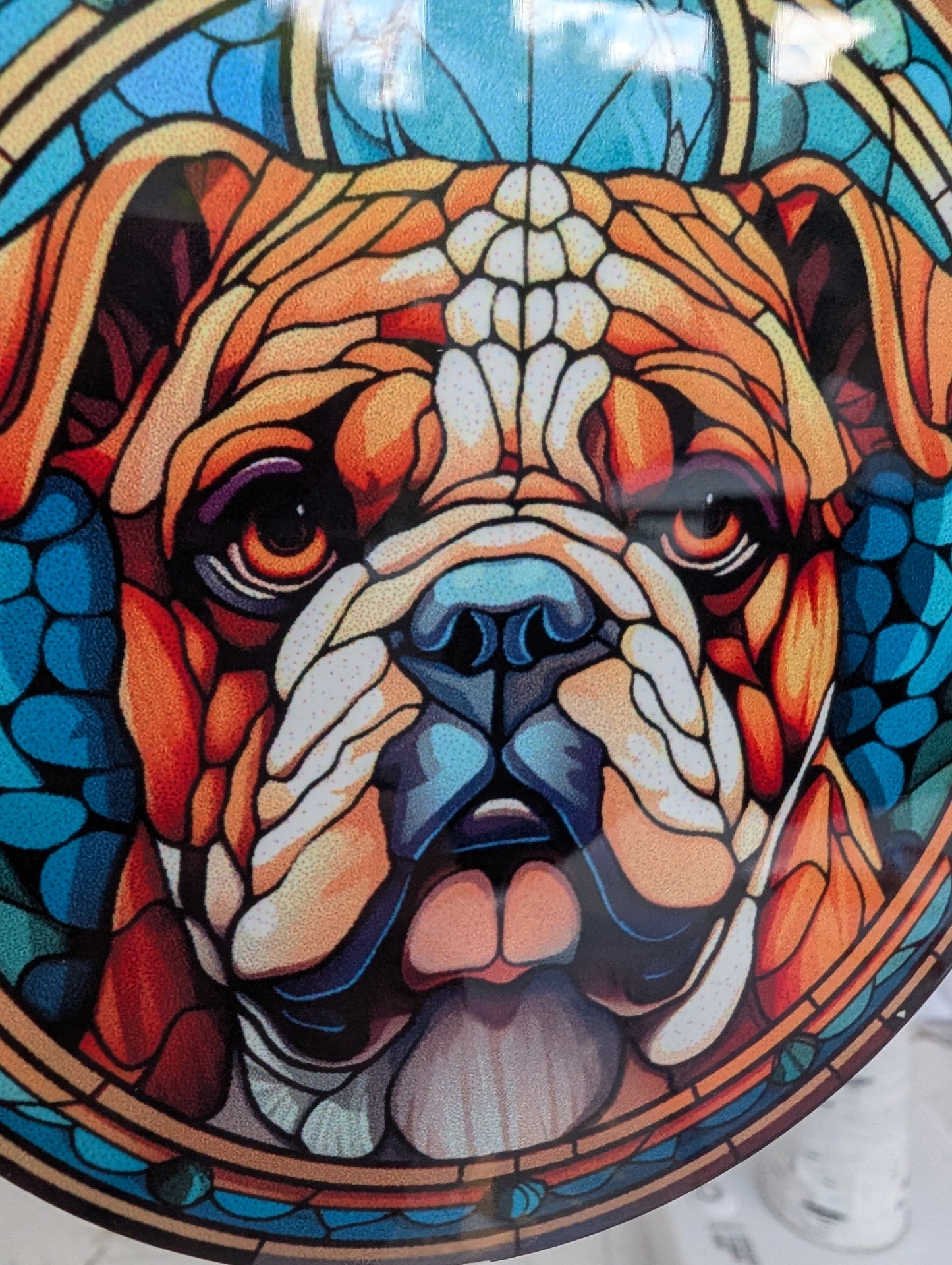 extreme close up of Bulldog hanging ornament in stained glass style, featuring a British Bulldog on a blue background, showing detail of Bulldog face