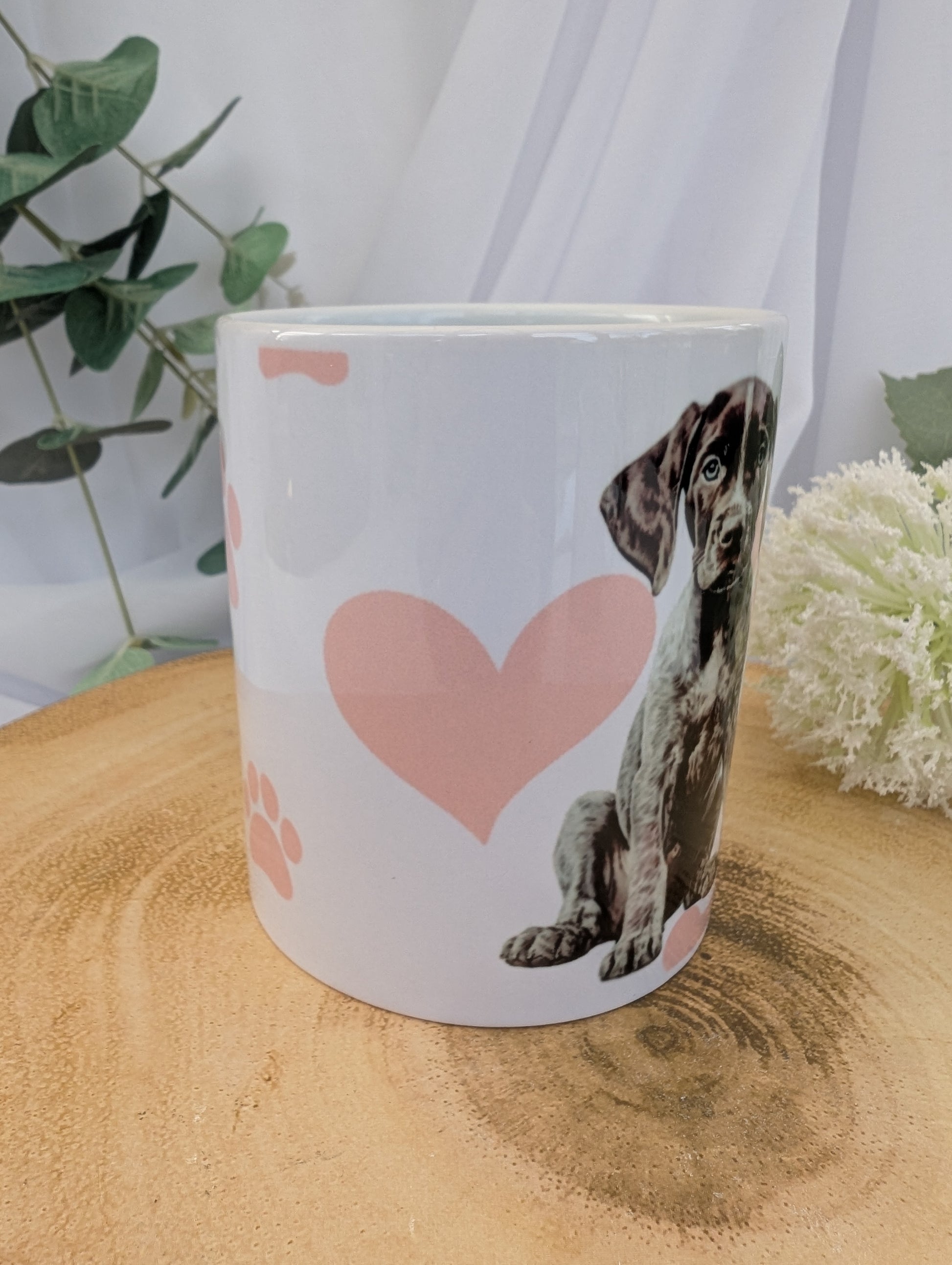 Side View of 11oz white ceramic German Short Haired Pointer Dog Mug with heart, paw and bone background in pink