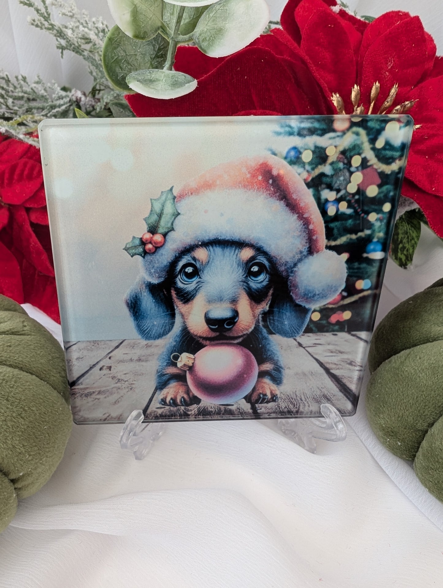 Dachshund Gifts - a cute Christmas- illustration of a dachshund puppy wearing a Santa hat and holding a pink ornament, surrounded by festive decorations.