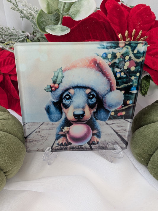 Dachshund Gifts - a cute Christmas- illustration of a dachshund puppy wearing a Santa hat and holding a pink ornament, surrounded by festive decorations.