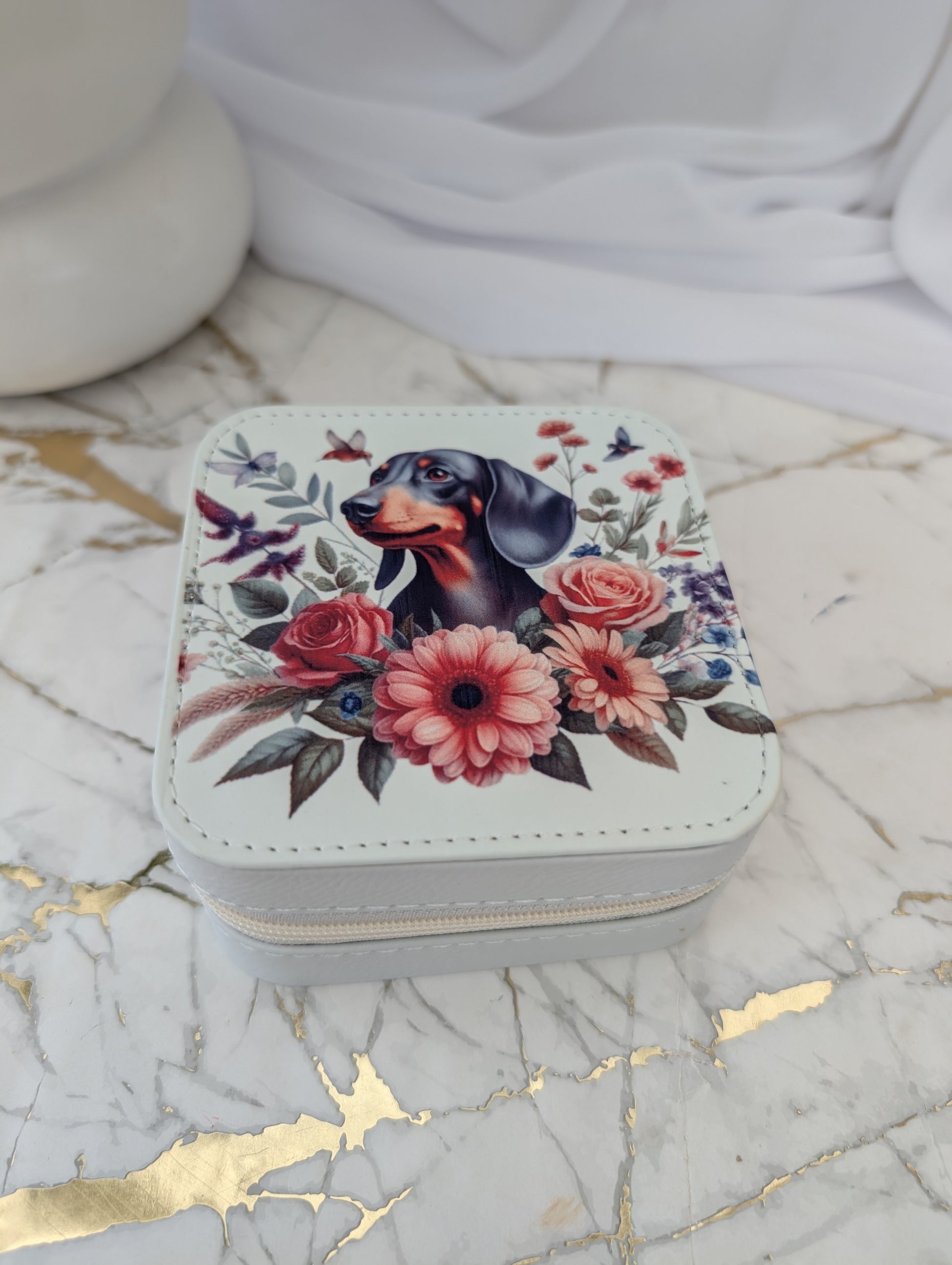 Small square jewelry box with floral and dachshund design on a marble surface