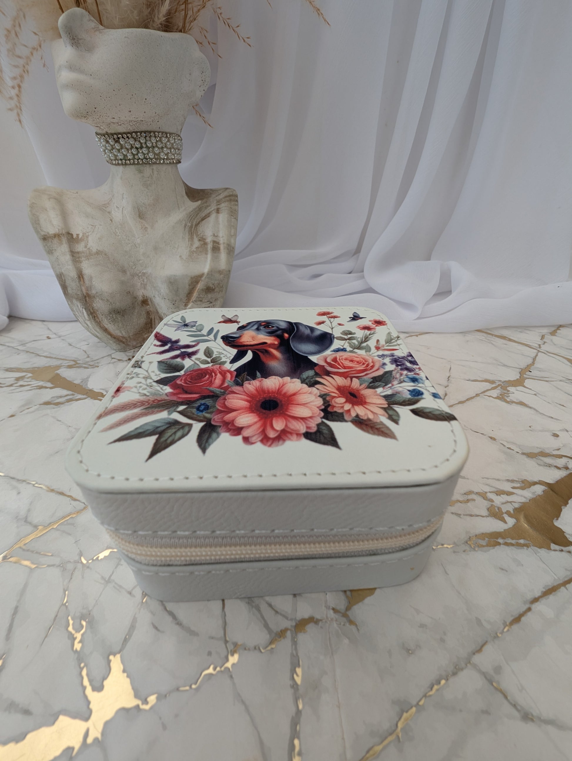 Small square travel jewelry box with dachshund dog and floral design on a marble surface