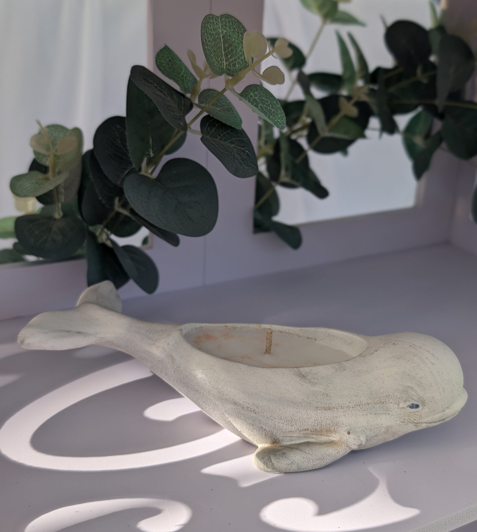 Decorative dolphin figurine on a surface with green foliage in the background