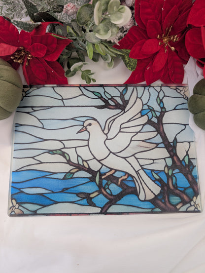 Stained glass-style chopping board of a dove on a branch with red flowers and greenery in the background.